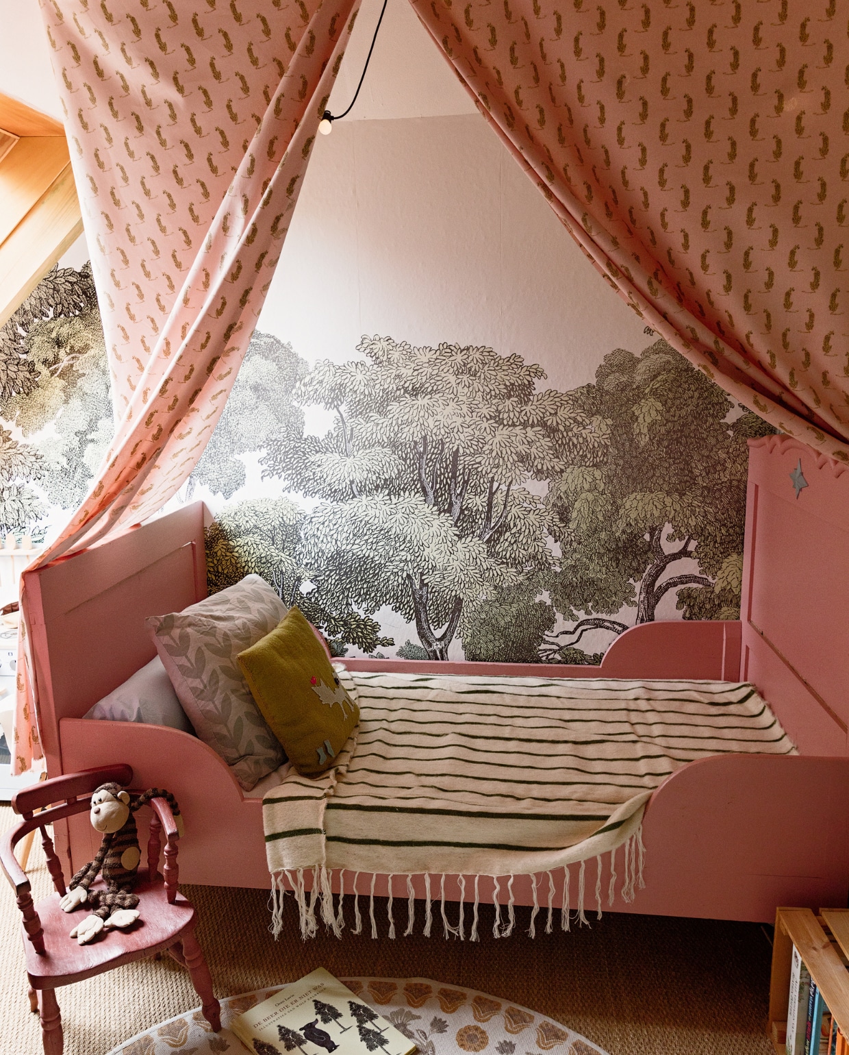 Behang Bellewood van Rebel Walls. Bed Marktplaats, zelf geschilderd. Stoel familiestuk Jean. Aap Jellycat. Klein kussen zelfgemaakt, blaadjeskussen Hema. Sprei The Souks. Stof hemelbed Kwantum. Vloerkleed Anthropology. Zeegras vloerbedekking. vtwonen 13-2022 | styling Ilona Jongepier | fotografie Dana van Leeuwen