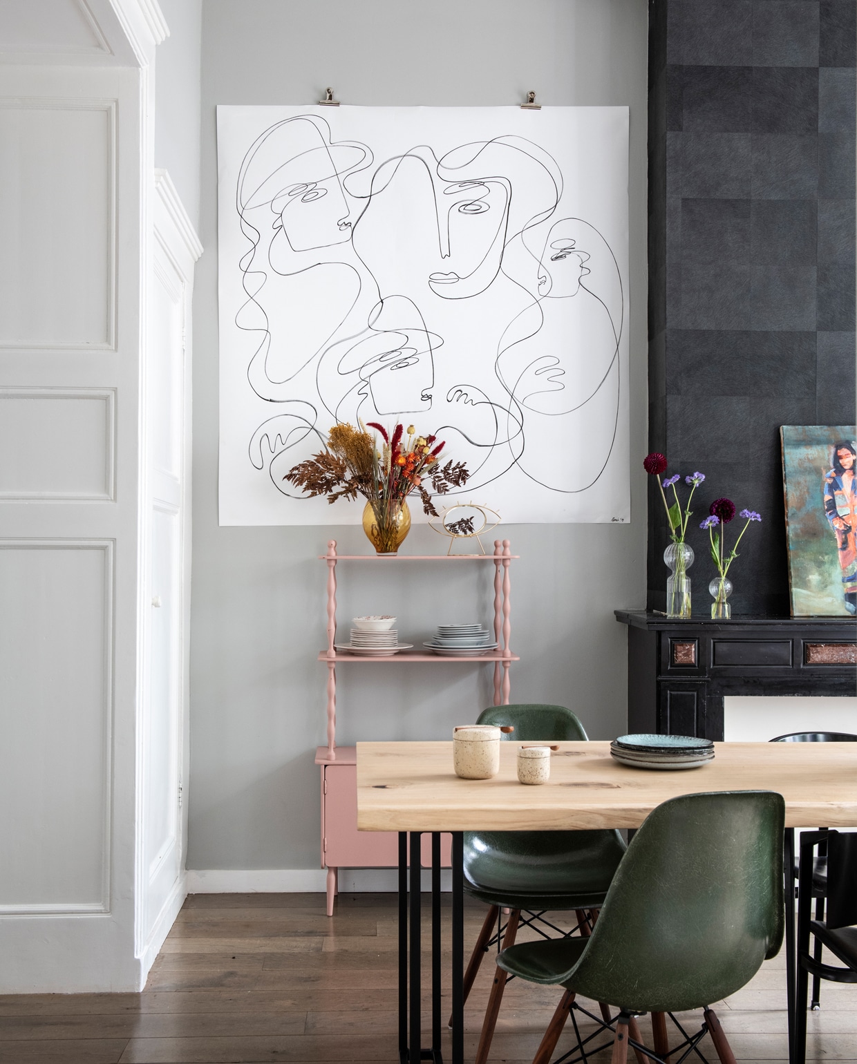 Aan de muur hangt een werk uit de collectie Entangled van Anne Mei Poppe. Houten eettafel van Wdstck, vintage Eames fiberglass stoelen van The Modern (modernvintage.nl), vintage kastje van All the Luck in the World. Droogbloemen van Aimelie. Het zwarte behang is nog van de vorige bewoners. Vaas op de kast cadeau gekregen, overige vazen &amp;klevering. Borden ‘van oma’ en tweedehandswinkels. Potjes H&amp;M. Op de schouw: kunst van Jasper Krabbé. vtwonen 1-2020 | styling Inge van Lieshout | fotografie Louis Lemaire | tekst Amber van Rijn