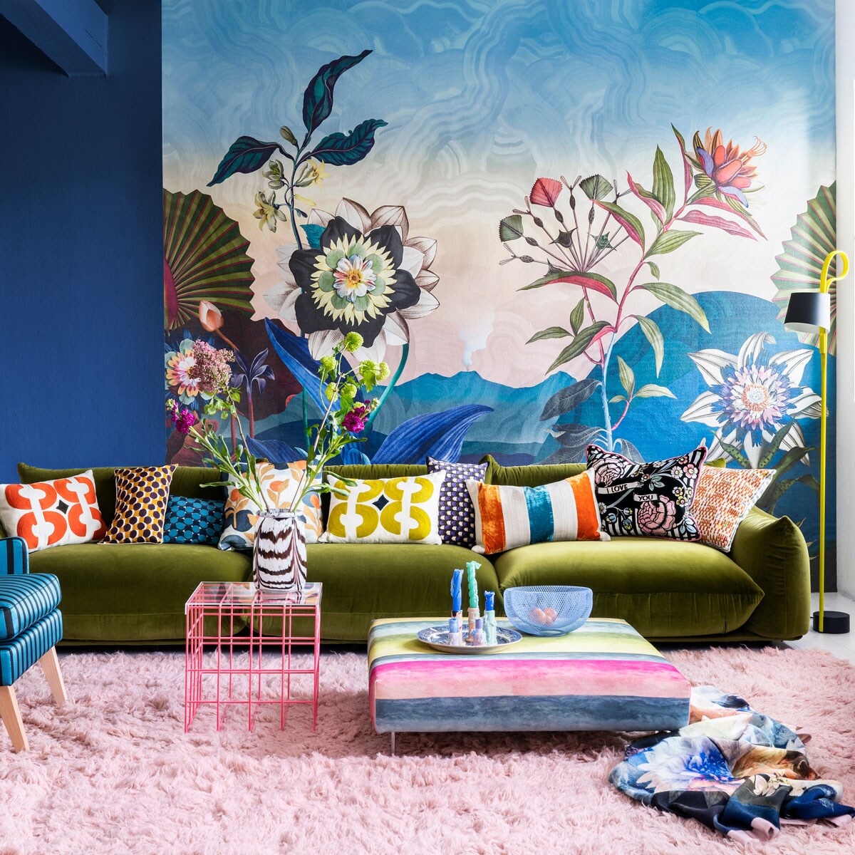 Paneel met behang Atlantis Aube van Christian Lacroix voor Designers Guild, 300×350 cm € 927,- (wva.nl). Blauwe muurverf Exciting Night No. 96 van Lab Paint, per liter € 45,- (vestingh.nl). Groene velours bank van Arflex, 96x354x70 cm (dxbxh) € 5709,-, roze fauteuil van Warm Nordic, 95x84x80 cm (lxbxh) € 2190,-, zachtroze hoogpolig wollen vloerkleed van Layered, 250×350 cm € 1090,- (goeds.nl). Multikleurige voetstoel in stof Rayure Chinoise Alchemilla van Designers Guild, 90×90 cm € 1485,-, oorfauteuil Harper Chair bekleed met stoffen van Christian Lacroix voor Designers Guild € 3220,- (wva.nl). Verstelbare vloerlamp € 659,- (hay.nl). Roze staaldraad tafel van Bold Monkey, 41x41x40 cm (lxbxh) € 165,- (boldmonkey.com). Kandelaars vanaf € 14,50, kaarsen van Hay, per 6 € 25,- (vtwonen.nl). Glazen vaas € 85,- (hay.nl). Vintage bord € 25,- (hetgroteavontuur.nl). Blauwe gaasschaal € 39,- (festamsterdam.com). Kussens van links naar rechts: rood geborduurd € 149,-, langwerpig model van zijde, per stuk € 89,- met bloemdessin € 109,-, groen geborduurd € 149,-, alles van Lelievre (loggerewilpower.com), velours streep van William Yeoward € 121,-, bloemen Christian Lacroix voor Designers Guild € 192,-, geborduurd € 132,-, wollen plaid van Designers Guild € 327,- (wva.nl). vtwonen 06-2022 | styling Marianne Luning | fotografie Stan Koolen