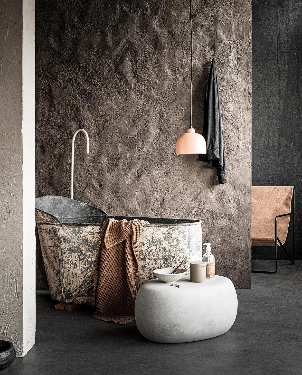 Muurverf in Heavy Clay (pure-original.nl). Zinken bad € 375,- (burbri.nl). Bijzettafel Pebble van vtwonen collectie € 149,- (basiclabel.nl). Stoel Desert Lounge Chair € 269,-, wafel handdoek Organic in tan € 39,-, zandkleurige ronde opbergdoos € 25,-, zeep € 25,-(fermliving.com). Hanglamp van Bloomingville € 105,-(vtwonen.nl). Schaal van gebakken klei € 75,- (couleurlocale.eu). vtwonen 03-2021 | styling Marlies Does | fotografie Sjoerd Eickmans