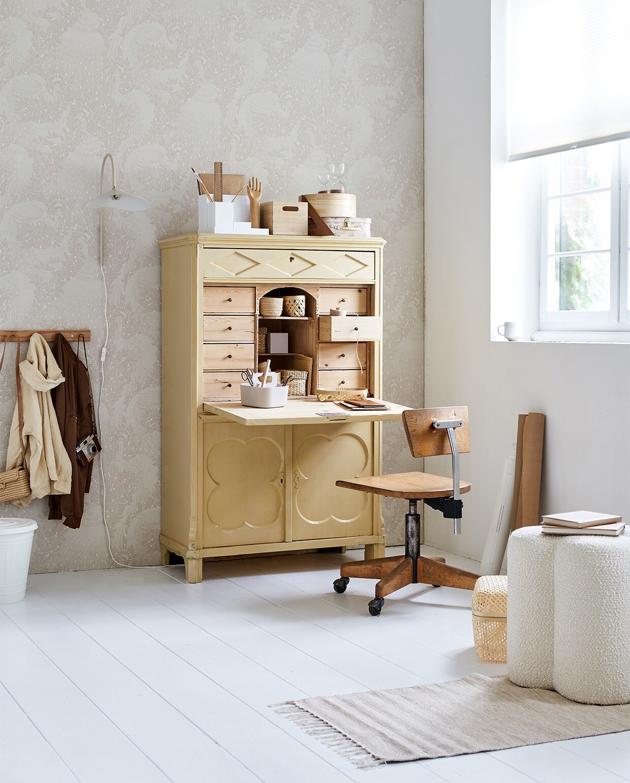 Vintage houten bureau € 495,- vintage draaibare bureaustoel € 125,- rieten mand met streep € 5,- rieten tas aan kapstok € 12,- (com-anders.nl). Behang Evelina Blush, rol van 10 m x 53 cm € 110,- (sandbergwallpaper.com). Zandkleurig geweven vloerkleed, 100×60 cm € 39,95, papieren koffer van Konges Sløjd, set van 2 € 24,-, witte organizer met hengsel van Liewood € 23,-, mok € 20,- (littledreamers.nl). Crèmekleurige ijzeren prullenbak met deksel Knodd, 40 liter € 19,99, witte bureauhouder Tjena € 3,99, zeegras mand met deksel Lurpassa, set van 2 € 9,99, houten krat Uppdatera € 19,99, ronde houten doos met deksel Mallgroda € 19,99, opengewerkte rieten mand voor pennen Saluding, set van 2 € 6,99, opengewerkte mand met deksel op de vloer Smarra € 19,99, houten kapstok Hövolm met 6 knoppen € 12,99, glazen zandlopers Eftertänka, 15 cm (h) € 6,99, 10 cm (h) € 4,99, wit verduisterend plisségordijn Schottis, 100×190 cm € 6,99 (ikea.nl). Beige bouclé poef Clover van Pols Potten € 270,-, ijzeren crèmekleurige wandlamp Arum in kleur Cashmere van Ferm Living € 289,- (vtwonen.nl). Overig privébezit. JA | vtwonen bijlage 08-2022 | styling Marlies Does | fotografie Bart Brussee