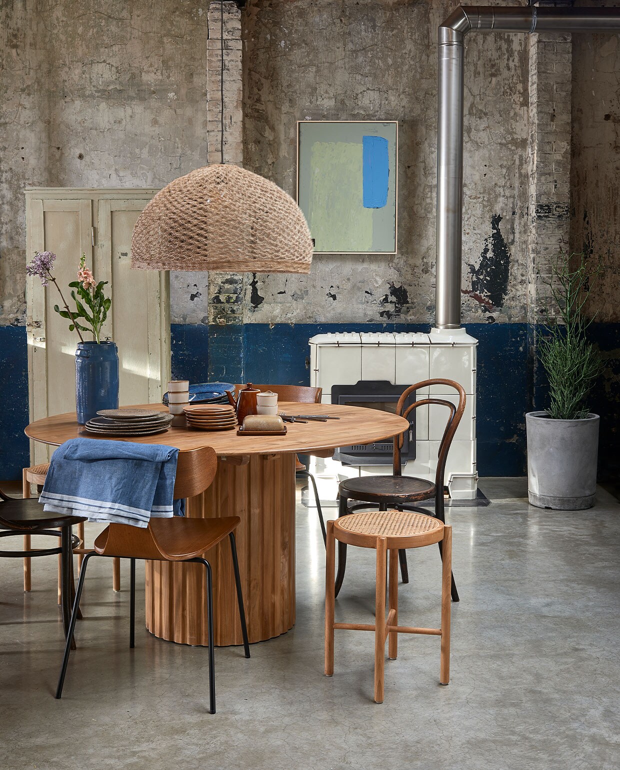Teakhouten eettafel Pillar, 140 cm () ? 1600,-, retro webbing kruk ? 149,-, diverse borden vanaf ? 7,50, mok ? 8,50, abstract schilderij, 6080 cm ? 349,- (hkliving.nl). Hanglamp, handgeweven uit India, 65 cm () vanaf ? 95,-, betonnen plantenbak XL, 4045 cm (xh) ? 195,- (boxworx.nl). Thonet stoel ? 195,- (neeflouis.nl). Houten stoel Form met metalen poten ? 199,- (deeekhoorn.com). Houten lockerkast ? 275,- (vandijkenko.nl). Tafelkleed 220145 cm ? 17,95 (ikea.nl). Blauwe vaas ? 53,- (fonq.nl). vtwonen 03-2022 | Styling Fietje Bruijn | Fotografie Dennis Brandsma\n