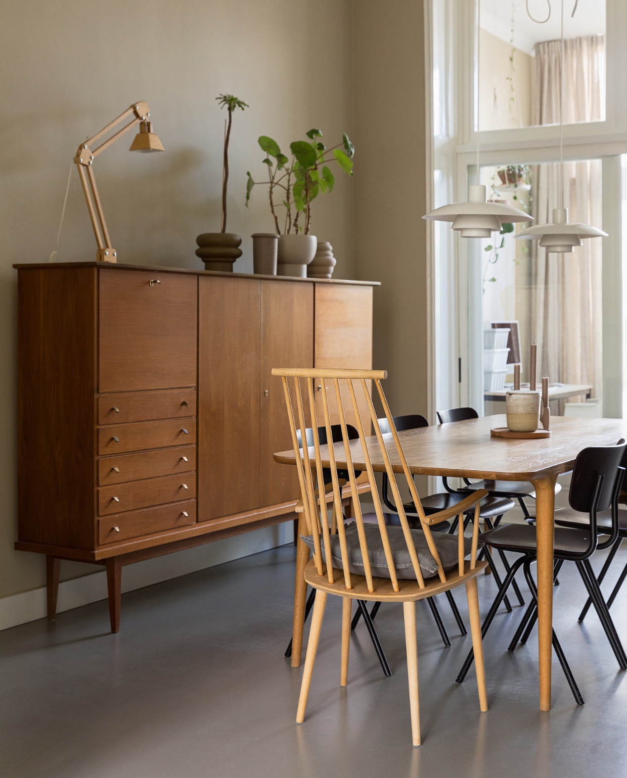 Muurkleur GN 080-08. Vintage Deense kast Marktplaats. Eettafel Fawn van Gazzda. Houten stoel Hay. Eettafelstoelen Dykmeyer via De Machinekamer. Tafellamp gekocht in Kopenhagen. Vintage plafondlampen PH4/3 van Louis Poulsen. Potten Nørd Conceptstore en rommelmarkt, planten via Nørd Conceptstore. Overig onbekend. vtwonen 10-2022 | Styling Ilona Jongepier | Fotografie Dana van Leeuwen