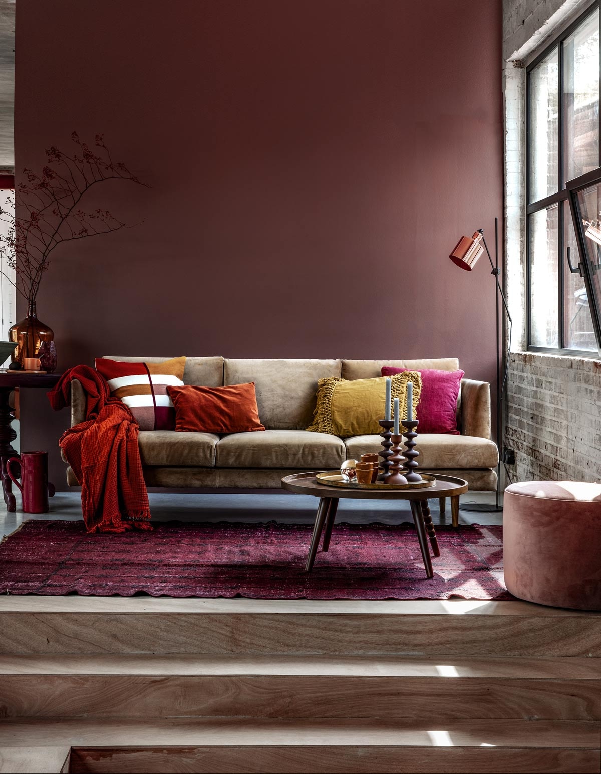 Muurverf Pure zijdemat Full Plum (Flexa). Beige velours 3-zitsbank Floyd, velours vintage Rosa poef (Sofacompany). Roestbruine crinkle plaid van HAY, vloerlamp Masterlight Industria 1020, okergeel kussen met franjes van Madam Stoltz (vtwonen.nl). Kussen met gekleurde vlakken, roestbruin velours kussen, okergeel kopje, okergeel bord (H&amp;M Home). Donkerfuchsia kussen Milazzo Peony van Designers Guild (Wilhelmine van Aerssen). Wijnrode bijzettafel (Combitex). Donkergele flesvaas (Van Dijk &amp; Ko). Olijfgroene schaal, donkerrode kan (In-Petto). Vloerkleed (Ochre and Red). Salontafel Arabica van Dutchbone, kandelaars laag, hoog, presse-papier met bloem (Woondock). Roestbruine kopjes (Intratuin). vtwonen 11-2018 | Fotografie Peggy Janssen | Styling Moniek Visser