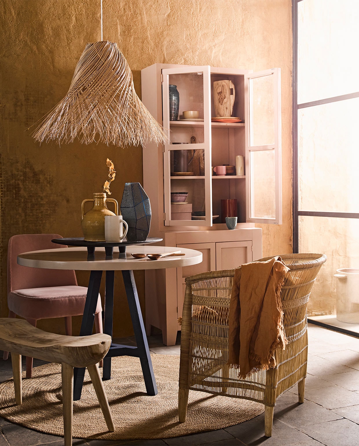 Ronde tafel met blauwe poot prijs op aanvraag, roze kast prijs op aanvraag (com-anders.nl). Hanglamp, gele vaas met oren, rond vloerkleed maat L, zwart dienblad, roze doos in kast, houten bord in kast, oranje bord in kast, bruin bord in kast, geel schaaltje, blauwe vaas linksboven in kast (loods5.nl). Bruin tafelkleed, snijplank, paarse kan, slabestek, bruin potje met deksel in kast, roze mok in kast prijs op aanvraag (hm.com). Blauwe mok, blauwe vaas op tafel (thingsilikethingsilove.com). Roze schaal op poot van HK Living (wonenmetlef.nl). Houten vaas in kast, paars schaaltje in kast links onder, lila schaaltje onder in kast (householdhardware.nl). Pot buiten, rode vaas in kast, beige vaas in kast middelste plank rechts (serax.com). Witte kan op tafel (annemiekebootsceramics.nl). Houten bankje van Mica links (vtwonen.nl). Roze stoel van stof (edha-interieur.nl). Stoel gevlochten hout (archive-store.nl). vtwonen 06-2019 | styling Liza Wassenaar | fotografie Alexander van Berge