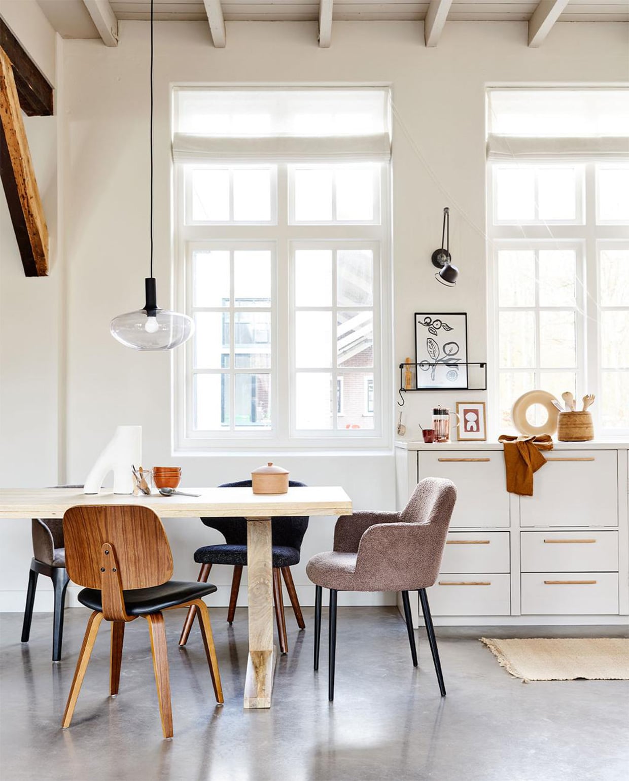 Mangohouten eettafel Deck in kleur Naturel, 200x90x78 cm (lxbxh) € 899,-, ook verkrijgbaar als ronde variant in kleur Clay, 120×78 cm ( Øxh) € 749,-. Linksachter: eetkamerstoel Scroll, met warmgrijze geweven stof, 53x50x76 cm (bxdxh) € 299,-. Rechtsachter: zwarte eetkamerstoel Cape, gemêleerde stof en hout, ook verkrijgbaar in blauw, 55x65x77 cm (bxdxh) € 199,-. Aan het hoofd: taupe eetkamerstoel Dining van geweven teddystof en metaal, ook verkrijgbaar in off white, 62x53x83 cm (bxdxh) € 249,-. Voor de tafel: walnoothouten eetkamerstoel Classic met PU lederen zitting, 48x50x81 cm (bxdxh) € 149,-. | m.m.v. vtwonen.nl (hanglamp Alton 35 van Nordlux, object op tafel van vtwonen, kommen op tafel HKliving, koperen perculator Leopold Vienna, terrakleurige kop HKliving, artwork Hôtel Magique), hm.com (vloerkleed). Overig privébezit. JA | vtwonen 02-2022 | productie Tanja Saarberg | styling Marlies Does | fotografie Bart Brussee | assistentie Neda Farzanyar, Judie Jonker