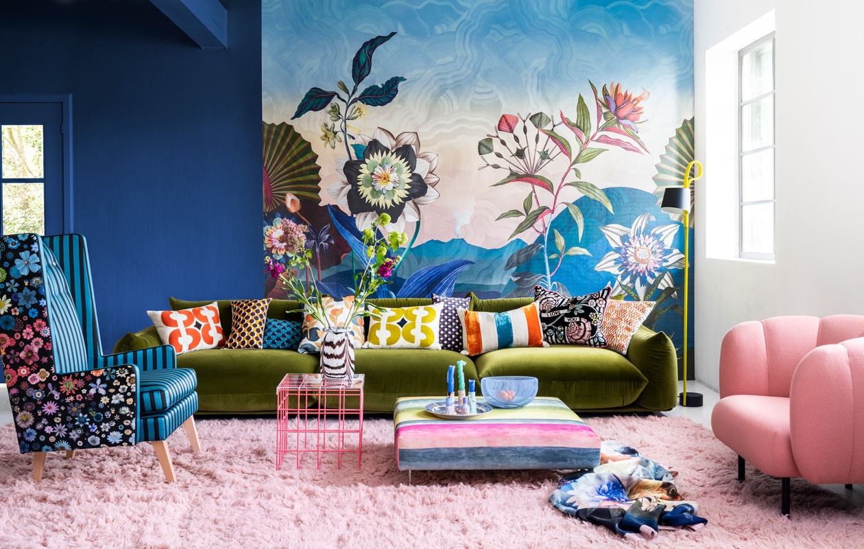 Paneel met behang Atlantis Aube van Christian Lacroix voor Designers Guild, 300×350 cm € 927,- (wva.nl). Blauwe muurverf Exciting Night No. 96 van Lab Paint, per liter € 45,- (vestingh.nl). Groene velours bank van Arflex, 96x354x70 cm (dxbxh) € 5709,-, roze fauteuil van Warm Nordic, 95x84x80 cm (lxbxh) € 2190,-, zachtroze hoogpolig wollen vloerkleed van Layered, 250×350 cm € 1090,- (goeds.nl). Multikleurige voetstoel in stof Rayure Chinoise Alchemilla van Designers Guild, 90×90 cm € 1485,-, oorfauteuil Harper Chair bekleed met stoffen van Christian Lacroix voor Designers Guild € 3220,- (wva.nl). Verstelbare vloerlamp € 659,- (hay.nl). Roze staaldraad tafel van Bold Monkey, 41x41x40 cm (lxbxh) € 165,- (boldmonkey.com). Kandelaars vanaf € 14,50, kaarsen van Hay, per 6 € 25,- (vtwonen.nl). Glazen vaas € 85,- (hay.nl). Vintage bord € 25,- (hetgroteavontuur.nl). Blauwe gaasschaal € 39,- (festamsterdam.com). Kussens van links naar rechts: rood geborduurd € 149,-, langwerpig model van zijde, per stuk € 89,- met bloemdessin € 109,-, groen geborduurd € 149,-, alles van Lelievre (loggerewilpower.com), velours streep van William Yeoward € 121,-, bloemen Christian Lacroix voor Designers Guild € 192,-, geborduurd € 132,-, wollen plaid van Designers Guild € 327,- (wva.nl). vtwonen 06-2022 | styling Marianne Luning | fotografie Stan Koolen