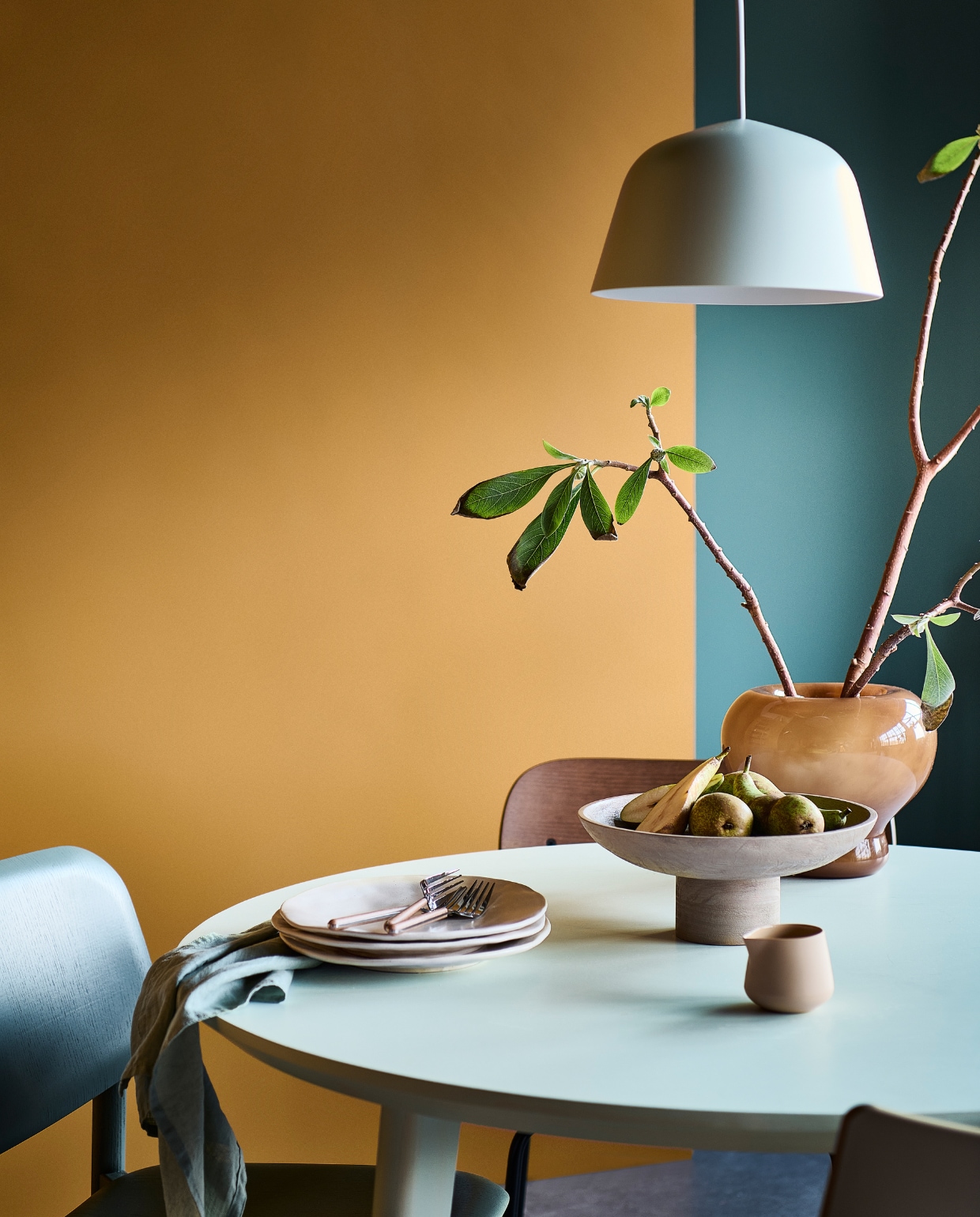 Muurverf links Desert, rechts Purple Blue van vtwonen, liter € 23,99, 2,5 liter € 39,99, lakverf tafel Ice, 1 liter € 41,99. M.m.v. vtwonen.nl (houten eetkamerstoel van Menu, petrolkleurige stoel van Hay, beige eetkamerstoel van Kartell), ikea.nl (eettafel), hm.com (glazen vaas, houten etagère, linnen servet), zarahome.com (aardewerken borden, bestek), dumu.nl (porseleinen melkkan).  vtwonen 1-2023 | productie Tanja Saarberg | styling Sanne Ketelaar | fotografie Sjoerd Eickmans