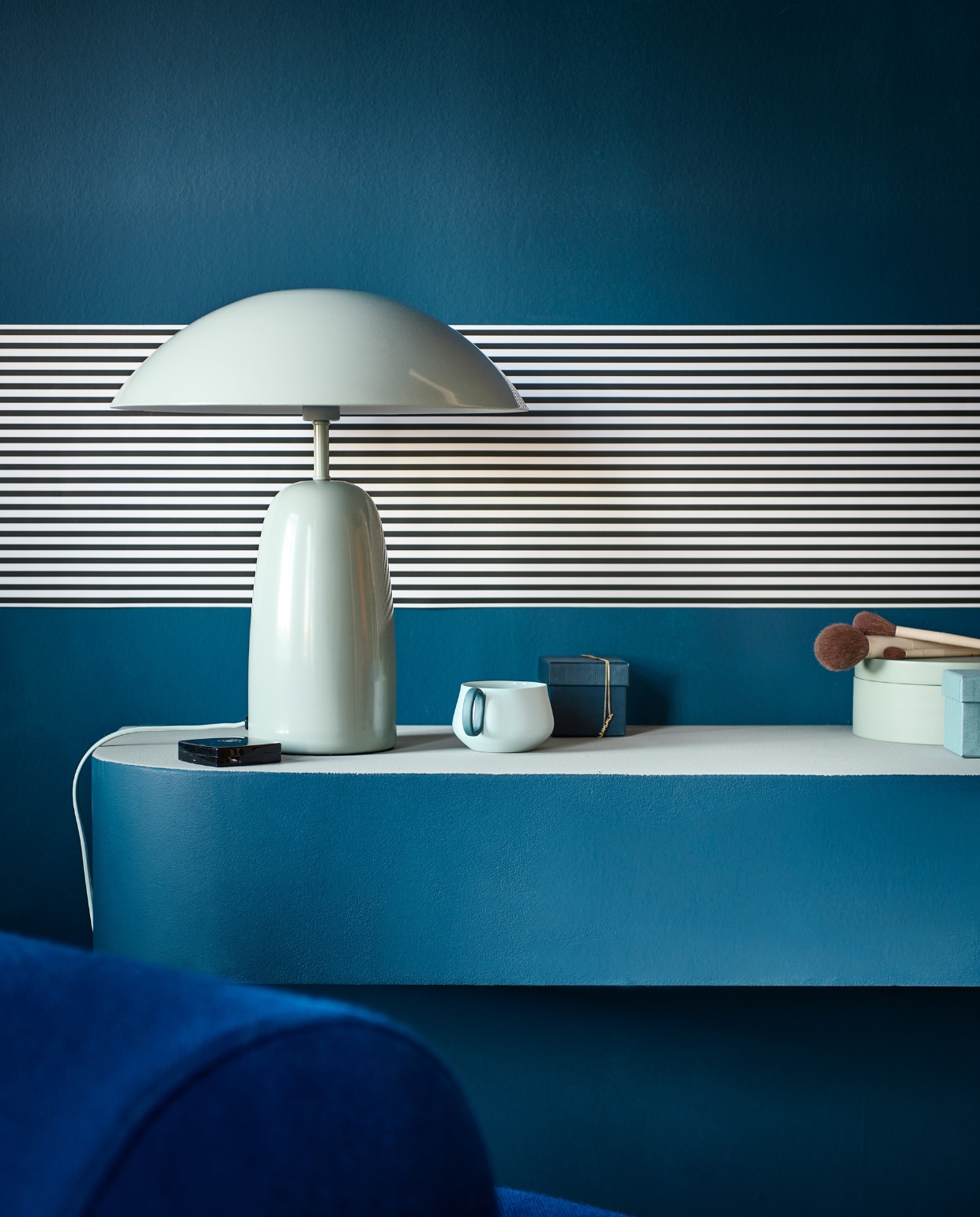Muurverf buitenkant en onderstel make-uptafel en wand Denim, bovenkant make-uptafel Soap van vtwonen, 1 liter € 23,99, 2,5 liter € 39,99. Behangstrook Streep Pitch Black/Egg White van vtwonen, rol 10 m x 100 cm € 14,99.M.m.v. hm.com (tafellamp, sieradendoos), festamsterdam.nl (fauteuil), dumu.nl (theekop). Overig privébezit. vtwonen 1-2023 | Productie Tanja Saarberg | Styling Sanne Ketelaar | Fotografie Sjoerd Eickmans