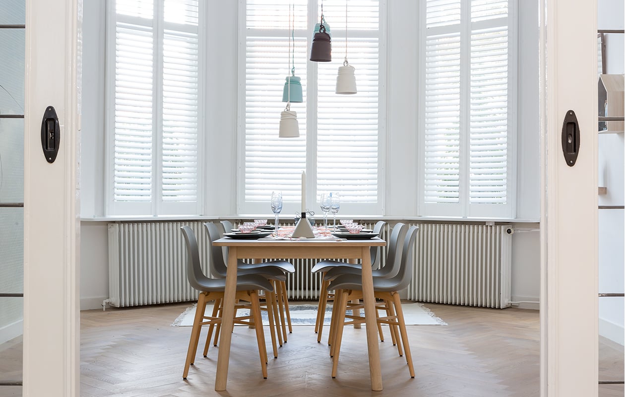 Shutters prijs op aanvraag (www.jasno.nl). Eetkamertafel Pause, 200x85x72 cm (bxdxh) € 640,- (www.eijerkamp.nl). Eettafelstoelen Langue Avant Garde Dining Chair, 50x51x78 cm (bxdxh) per stuk € 229,- (www.norr11.com). Hanglampjes Cable Light van porselein, per stuk € 179,- (www.patrickhartog.nl). Diverse wandplankjes prijs op aanvraag (www.fijnhout.nl). Groene vaas € 24,95 (www.vtwonen.nl). Op tafel: champagneglazen Figures € 11,25 (www.estherx.nl). Blauwe kom van vtwonen, Ø 14 cm € 6,95, grijze kom van vtwonen, Ø 14 cm € 6,95, grijs bord van vtwonen, Ø 16 cm € 6,95, blauw bord van vtwonen, Ø 26,5 cm € 16,95, blauwe serveerschaal van vtwonen, Ø 30 cm € 34,95 (www.vtwonen.nl). Betonnen kandelaars Conic, per stuk € 29,95 (www.puik-art.nl). Vilten loper € 65,- (Vilta Amsterdam). Roze schaaltjes, glaasjes, Mariabeelden privébezit. vtwonen 03-2017 | styling Frans Uyterlinde | fotografie Barbara Kieboom