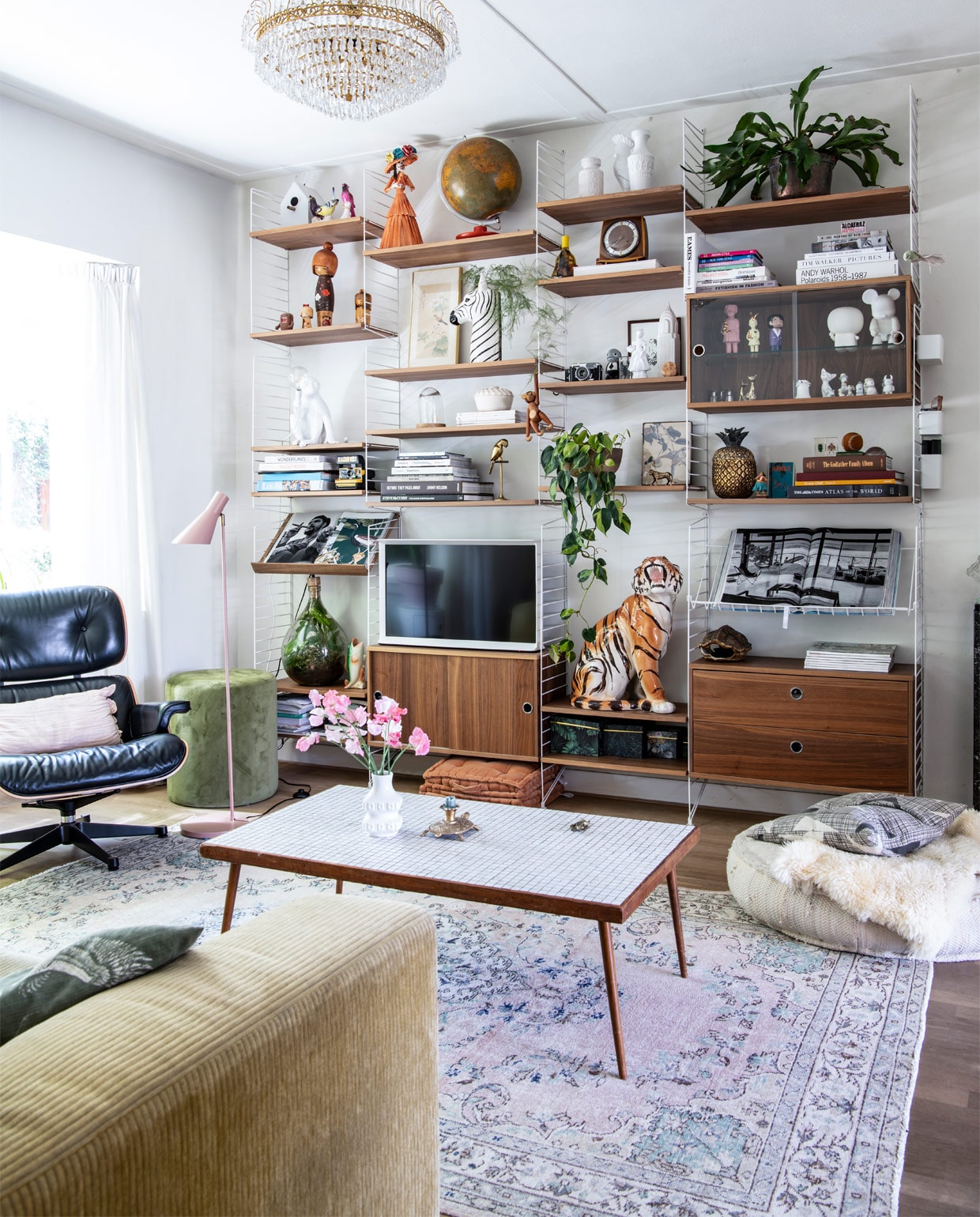 Bank Leolux, kleed Rozenkelim. Eames Lounge Chair en String-kast Co van der Horst. Plafondlamp straatvondst, vloerlamp Kwantum. Groene poef Riverdale, matraskussens Day Home, ecru poef Lodsh. Kussen Livv lifestyle. Tafel en ornament kringloop, kandelaar Sissy-Boy, vaas West Germany. In kast: zebra- en visvaas en lijst met print Sissy-Boy, aap Kay Bojesen, tijger, ornament vogel en klok Dolores del Dia. Tekening Mark van Gennip (mrrk.nl), ananas Zara Home. Overige souvenirs en vintage. vtwonen binnenkijk special 12-2020 | productie Insidehomepage | styling Kim Timmerman | fotografie Louis Lemaire | tekst Inge van Lieshout | tekstbewerking Mariska keus