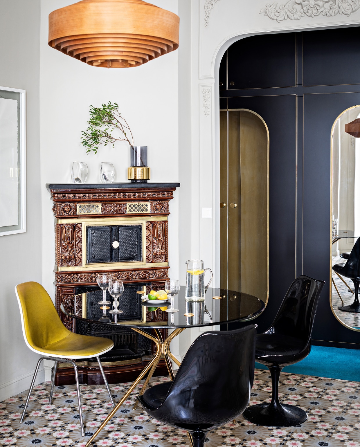 Teakhouten wandkast, houten hanglamp, glazen Emil Stejnar-hanglamp, eettafel en zwarte stoelen van KnollStudio vintage. Gele stoel Eames DSX Vitra. In de op maat gemaakte wandkasten op de achtergrond zijn spiegels verwerkt. Overig onbekend. vtwonen special binnenkijken 2022-3 | Productie AC Scoffoni | Styling Marie-Maud Levron | Fotografie Yann Deret | Tekstbewerking Renate Dahlmans