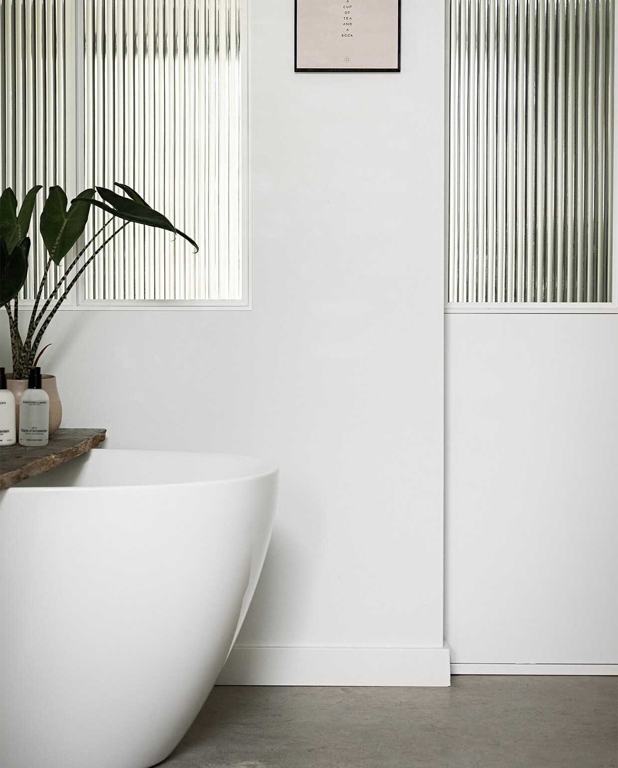 Muurkleur Ral 9016, vloer gevlinderd beton van Bull beton. Bad Hornbach, plant Intratuin, plank gevonden, zeepflessen Marie-Stella-Maris. JA | vtwonen 12-2022 | styling Ilona Jongepier  | fotografie Dana van Leeuwen