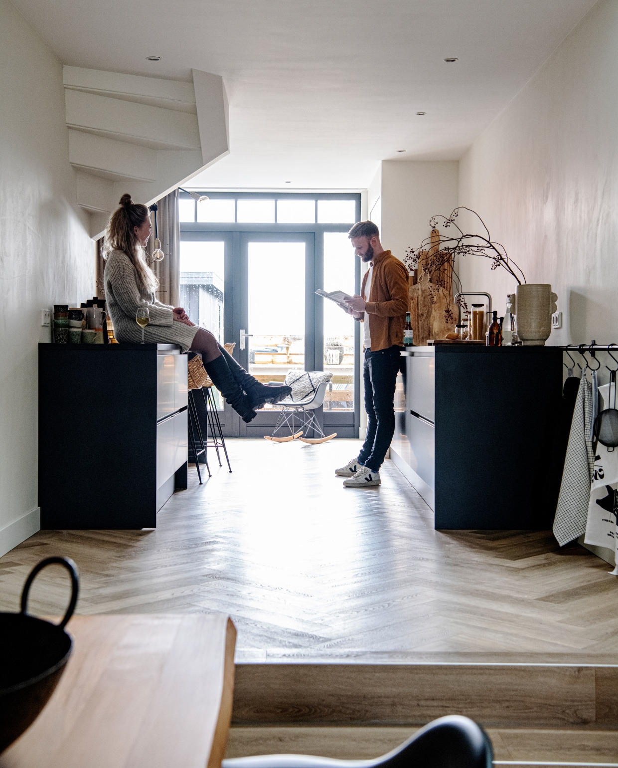 Muurverf RAL 9010. Vloer naturel eiken visgraat pvc. Keuken Keuken Kampioen. Barstoelen MeubelAsia. Mokken en kan HKliving. Eames-schommelstoel Vitra. Kussen in stoel HKliving. Houten planken Pluk, Xenos en Loods 5. Voorraadpotten Loods 5, zeeppompjes Wellmark. Vaas Urban Nature Culture. Steigerbuis Karwei, haken Dille &amp; Kamille. Theedoeken Dille &amp; Kamille en Elias. Overig onbekend. vtwonen 12-2022 | productie InsideHomePage | styling Studio Marit Saladini | fotografie Louis Lemaire