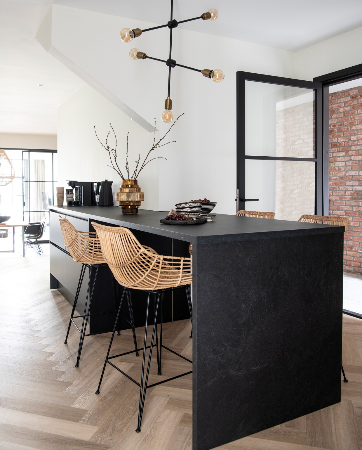 Muurverf RAL 9010. Vloer naturel eiken visgraat pvc. Keuken Keuken Kampioen. Barstoelen MeubelAsia. Mokken HKliving, zwarte waterkoker Alessi, vaas tuincentrum, kommen en bord uit Marokko. Lamp House Doctor. Overig onbekend. vtwonen 12-2022 | productie InsideHomePage | styling Studio Marit Saladini | fotografie Louis Lemaire