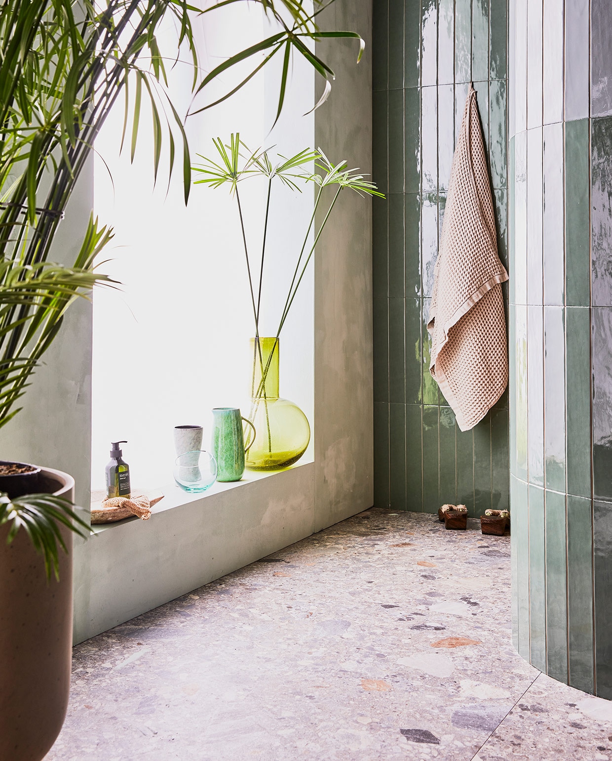Donkere wandtegel Marrakesh, kleur Army Green, glans, 6,5×40 cm. Lichte wandtegel Marrakesh, kleur Seagreen, glans, 6,5×40 cm. Vloertegel Composite, kleur Multicolor, 120×120 cm.M.m.v. vtwonen.nl (badlakens van Marc O’Polo), nordal.eu (plantenpot), bungalow.dk (groene kan), hm.com (handzeep Meraki), hkliving.nl (grote groene glazen vaas). Overig privébezit. vtwonen 08-2021 | productie Tanja Saarberg | styling Cleo Scheulderman | fotografie Jeroen van der Spek\n\nvtwonen 08-2021 | tropische badkamer met groene tegels en vaas en plant