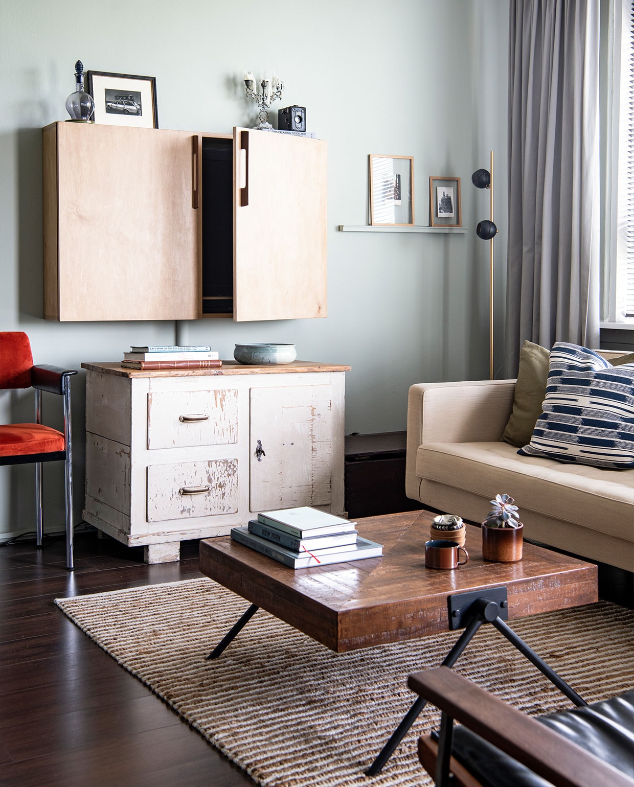 Vloer Ikea, muurverf Mizzle van Farrow &amp; Ball. Oranje stoel cadeau, vloerkleed Zara Home, televisiekast zelfgemaakt met grepen van Woodchuck, kast en kandelaar vintage, karaf erfstuk, kom souvenir, ingelijste mezzotint van Sjoerd Tegelaers. Bank Loods 5, kussens H&amp;M Home, vloerlamp Leen Bakker, bijzettafel cadeau, vazen en pot erfstukken, koffie­tafel boeken Thank you so much. It was awful van Guy Vording, New York van Hannibal Books, Most People Are Idiots van Guy Vording, gordijnen Hema. NEE | vtwonen 6-2022 productie Insidehomepage | styling Kim Timmerman | fotografie Louis Lemaire  | tekst Anne-Flore Muller