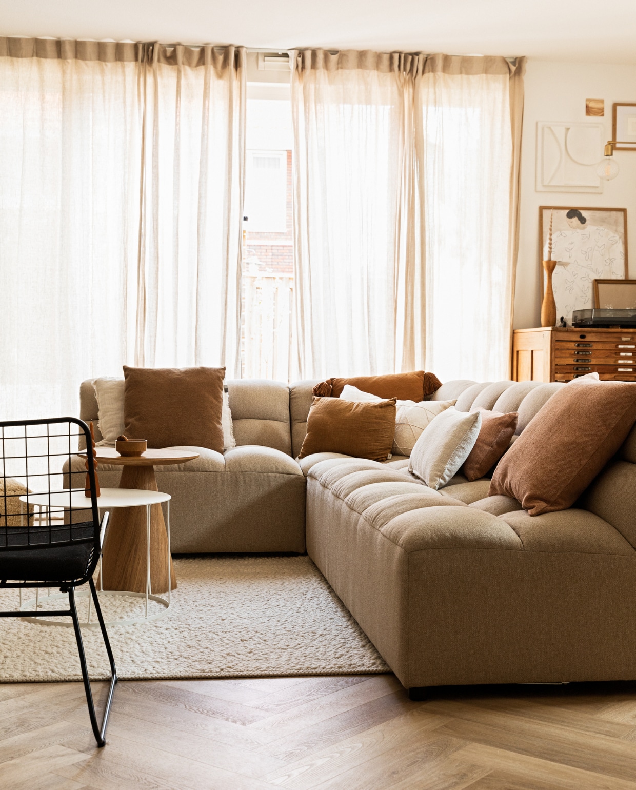 Bank Karwei, witte salontafel van k’willem in huis, houten bijzettafel Kwantum, kussens via Bij Emma Thuis en Mamoesjka, gordijnen Ikea, draaikaars op tafel Dille &amp; Kamille, vloerkleed en witte salontafel via Marktplaats, draadstoel Karwei, ladenkast Marktplaats, posters PSTR Studio, 3D-kunstwerk zelfgemaakt, klein houten kunstwerk Ruben van der Scheer, kandelaar van kringloopwinkel, wandlamp House Doctor, platenspeler Pro-Ject. JA | vtwonen 09-2022 | styling Ilona Jongepier | fotografie Diana van Leeuwen | tekst Chris Muyres