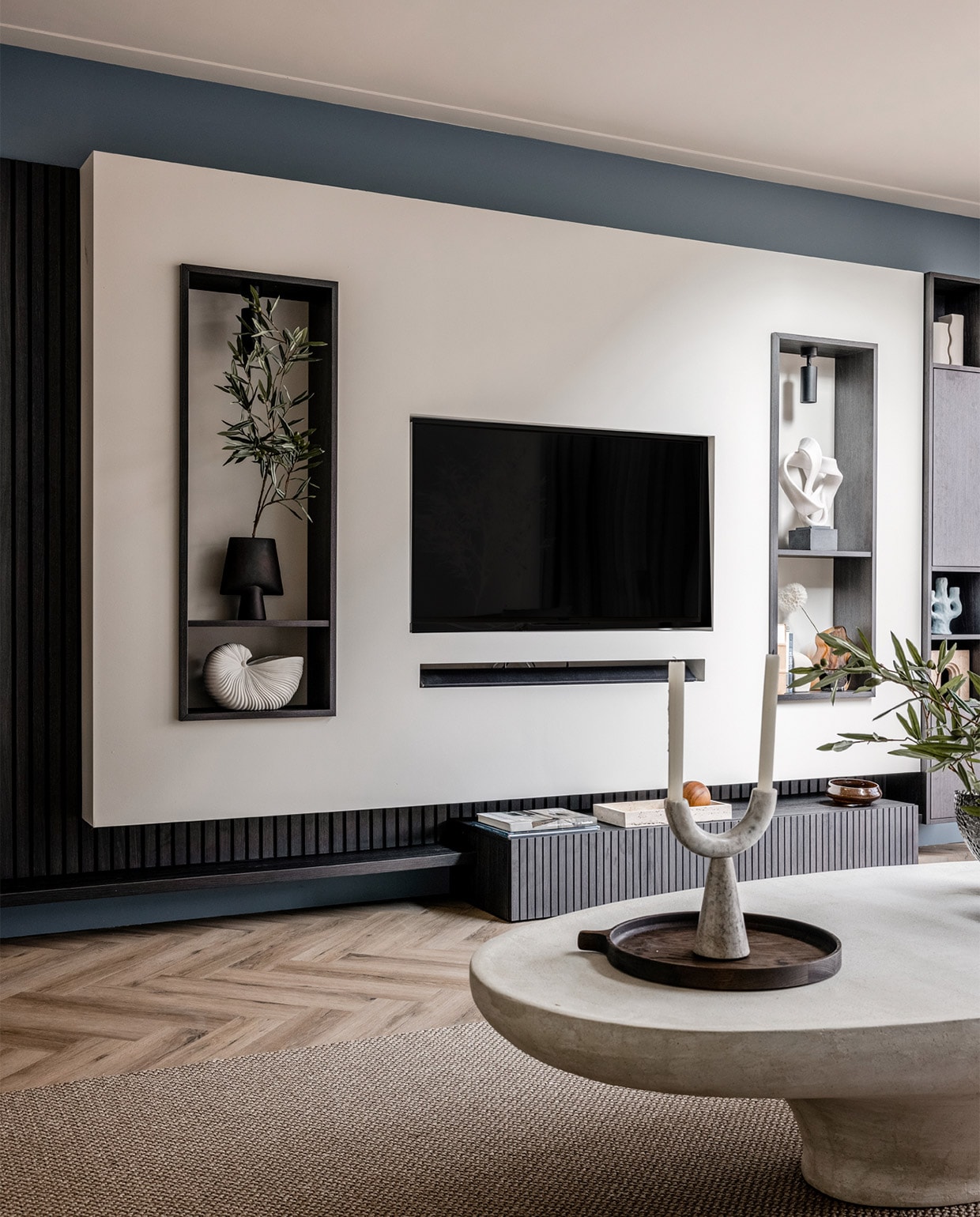 Flexa Creations muurverf Denim Drift (flexa.nl). Plafondspots in de kast € 64,95 (lightinova.com). Wandmeubel met een verticale lattenwand en ledverlichting vanaf € 5800,- (meijermaatinterieurs.nl). Sisal vloerkleed Luca in uitvoering 6704 € 2550,- (cunera.nl). Salontafel € 1599,- (lanena-home.com). Bank, per element vanaf € 850,-, donkergrijze vaas in de linker nis € 65,-, blauwe kandelaar € 38,50, zwart ornament op de salontafel € 22,99, vazen op de salontafel, per stuk vanaf € 185,-, houten dienblad € 169,- (eijerkamp.nl). Witte schelpenvaas van Ferm Living € 85,15, blauwe plaid van Malagoon € 39,95 (vtwonen.nl). Witte vazen in de kast rechts, set van 2 € 14,99, bruine vaas € 24,99 (hm.com). Notitieboek € 35,65 (badenbaden.nl). Beige object in de kast rechts € 249,-, dienblad waar de houten bal in zit € 169,- (stonedamsterdam.com). Marmeren siervorm op voet € 155,78, kandelaar op salontafel € 69,69 (nordal.dk). Kaarsen, per stuk € 1,- (hema.nl). Olijftak 138217, prijs op aanvraag (silk-ka.com). Overig privébezit. JA | vtwonen weer verliefd op je huis | seizoen 17, aflevering 4 | styling Liza Wassenaar | fotografie Sonja Velda