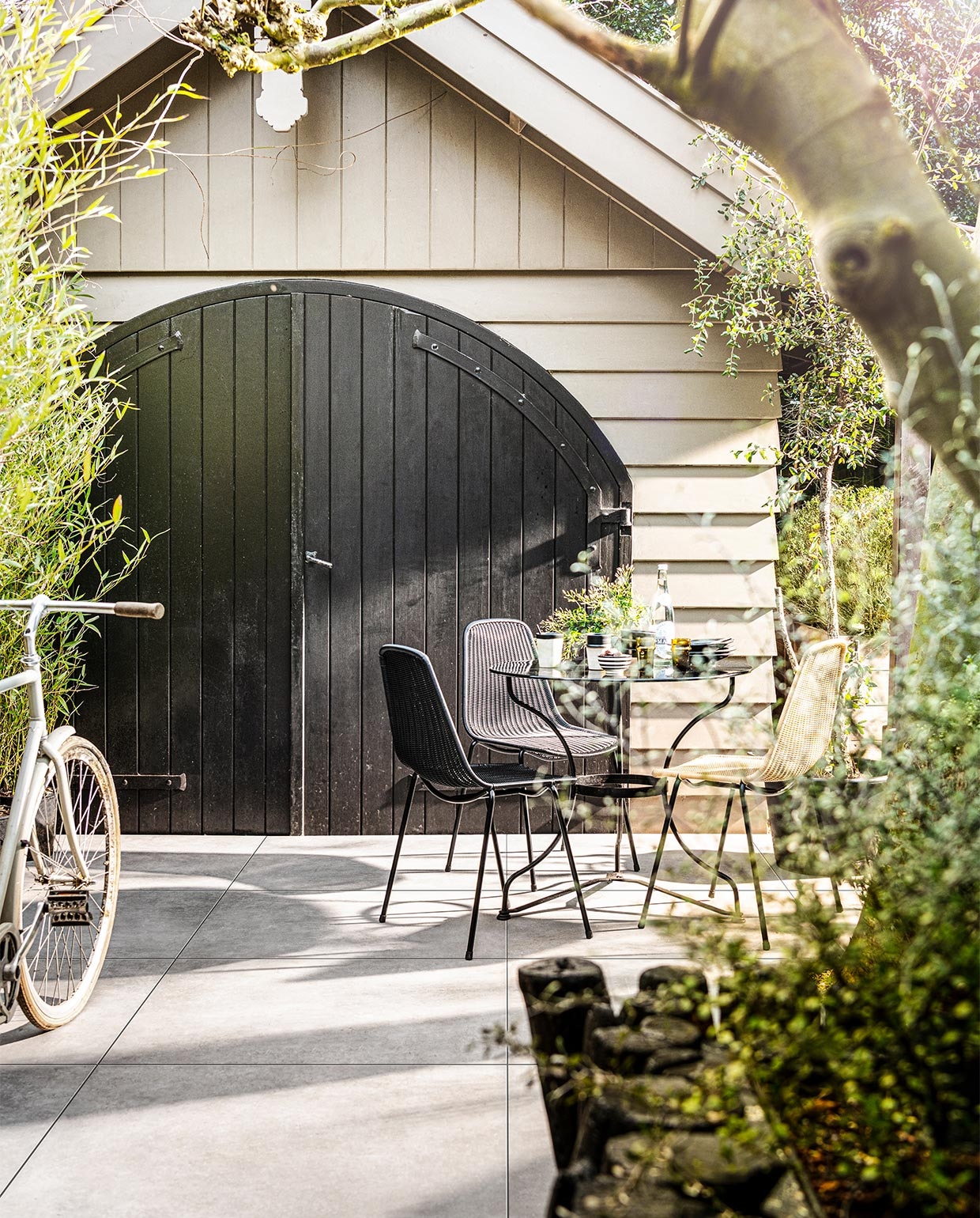 Tegels Solostone Uni Mold Grit, 90x90x3 cm (lxbxh) per m² € 80,- (ook verkrijgbaar in Basalt, en in Grit, Basalt en Taupe in 70x70x3,2 cm). M.m.v. householdhardware.nl (servies, mokken, glazen, schaaltje), bymolle.com (stoelen Basket Chair). Overig privébezit. JA | vtwonen 03-2021 styling Kim van Rossenberg | fotografie Sjoerd Eickmans
