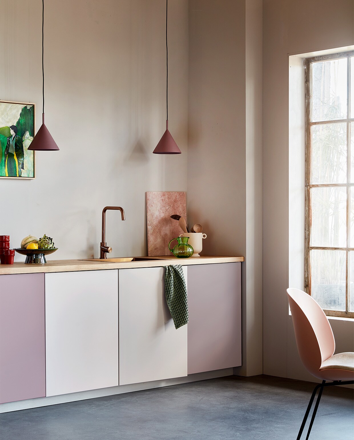 Muurverf Flexa Easycare Keuken kleur Cosmic Glory, per liter € 25,49, verf kastdeuren Flexa Mooi Makkelijk Keukenkasten kleur Cosmic Glory, Pink Nudity en HeartWood, per 750 ml € 37,49 (flexa.nl). Keukenkasten basiselement Metod, 60x60x80 cm (bxdxh) € 38,-, deur Veddinge, 60×80 cm (bxh) € 23,-, aanrechtblad Karlby, massief hout met eiken fineer, 186×63,5×3,8 cm (lxbxh) € 139,- (ikea.com). Koperen kraan € 315,-, spoelbak € 349,- (caressi.com). Paarse hanglampen Triangle € 95,- (hkliving.com). Roze stoel van Gubi € 705,- (stockdutchdesign.com). Rode mokken € 9,95, pollepels large € 9,95 (householdhardware.com). Kunstwerk French Nature met lijst, 40×50 cm (bxh) € 239,-, groene schaal met voet, 30 cm (Ø) € 69,-, marmeren snijplank, 50×40 cm € 109,-, groene glazen karaf € 38,- (hkliving.com). Keramieken pot € 14,95 (hm.com). Linnen theedoek € 14,95 (hetlinnenhuis.nl). vtwonen 09-2022 | styling Leonie Mooren | fotografie Peggy Janssen