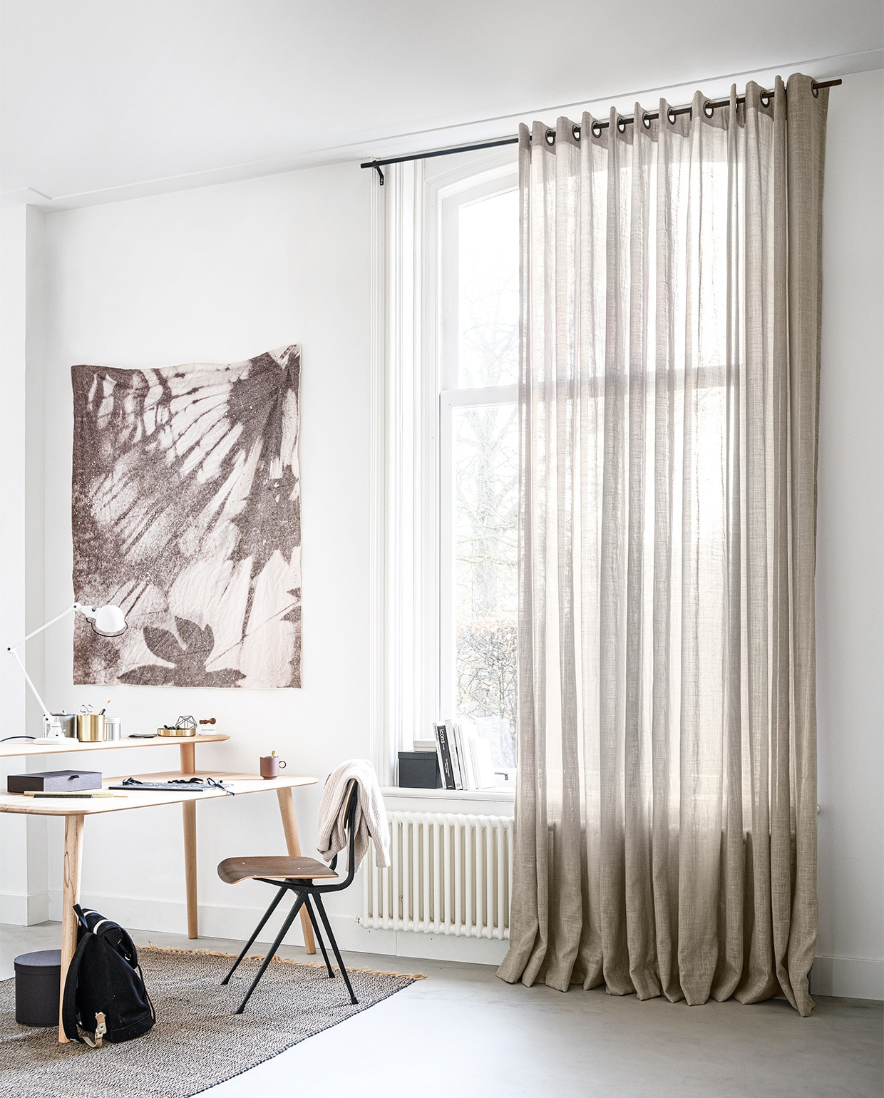 Gordijn op maat (2x) in stof Tweed met Wave plooi kleur 1147, per meter € 23,99uit vtwonen collectie. Transparant gordijn op maat in stof Weave kleur 2713, per meter € 27,99. M.m.v. hkliving.nl (fauteuil, vloerkleden, baklijst met artwork, schaal op voet, kist van hout), basiclabel.nl (bank Sleeve van vtwonen), loods5.nl (salontafel, kast, mok, theepot), hm.com (kussens op bank, wollen trui, marmeren opbergdoos, marmeren bal, glazen windlicht), extravert.nl (Jieldé lamp), marie-stella-maris.com (roomspray), adidas.nl (sneakers). Overig privébezit. JA | vtwonen 13-2020 | styling Marlies Does | fotografie Sjoerd Eickmans | productie Tanja Saarberg