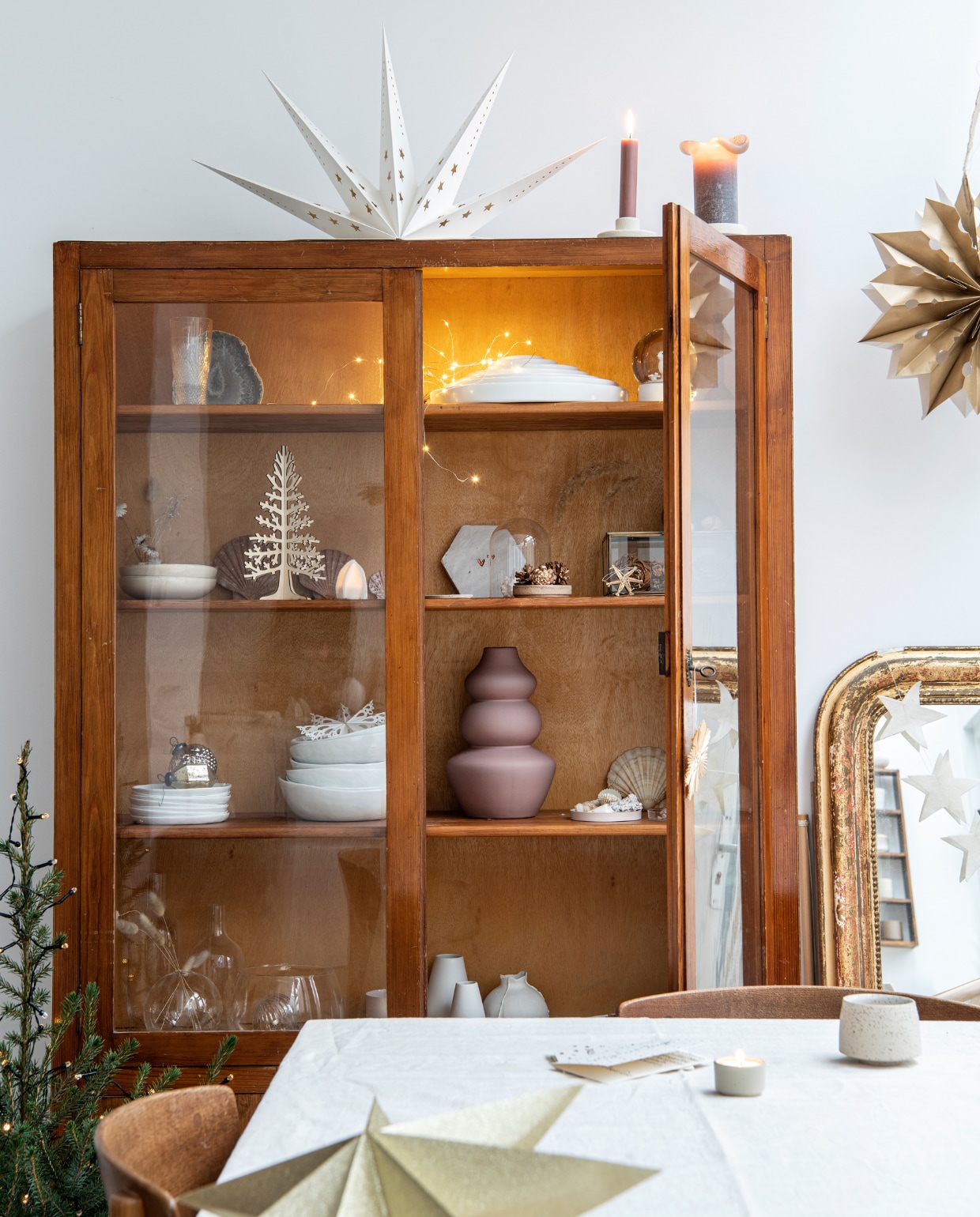 Eettafel: schragen Hay, blad Pontmeyer, zelf geschilderd en bevestigd. Stoelen Dille &amp; Kamille. Tafelkleed en kandelaars H&amp;M Home. Kan Cube White Conceptstore, glas met gouden rand Hay, kristallen glazen erfstuk. Kerstdecoratie Sissy-Boy, spiegel Frans vintage, sterrenslinger zelfgemaakt. Kast Marktplaats. vtwonen 13-2022 | productie Insidehomepage| styling Myla Griese | fotografie Louis Lemaire