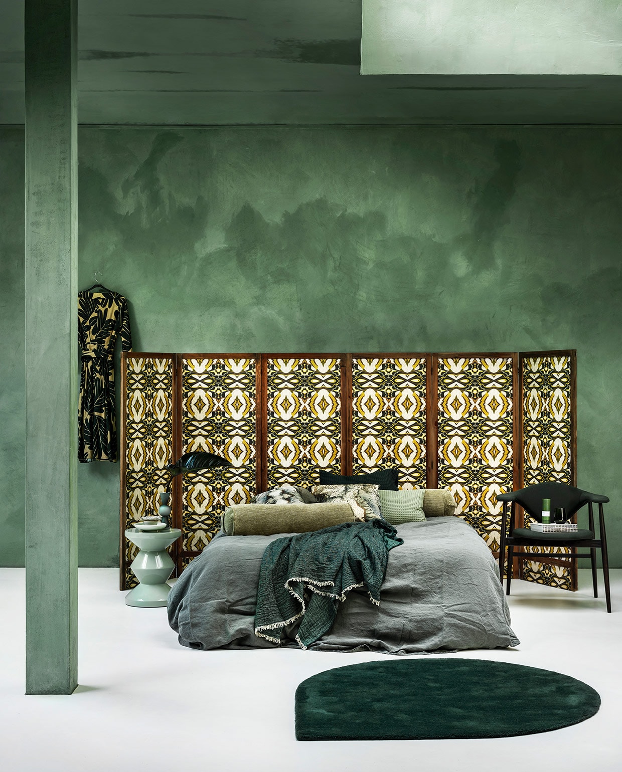 Panelen prijs op aanvraag (com-anders.nl) met daarop behang Casca Belle van Hanneke van de Pol, per rol € 99,95 (artwallcollection.com). Linnen dekbedovertrek, 240×220 cm € 149,95, groene plaid € 99,95, wafelstoffen kussen € 14,95 (vandyckshop.nl). Rolkussen € 32,95 (hkliving.nl). Kussens met dessin van Chantal Keizer € 89,95 (est1966.nl). Mintgroene bijzettafel € 245,- (polspotten.nl). Stoel Masculo van Menu € 1200,-, druppelvormig vloerkleed Stilla van Aytm € 399,- (goeds.nl). Vaas van Design House Stockholm € 42,20 (vtwonen.nl). Kom € 28,- met salie € 8,50, groene koker met matcha Whisk Antwerp € 24,99 (thewhitedoorstudio.nl). Groen glas per 2 € 64,90 (iittala.com). Jurk (natan.be). Kalkverf Lagune, per liter € 48,- (cartecolori-dialma.nl). vtwonen 01-2021 | styling Marianne Luning | fotografie Stan Koolen