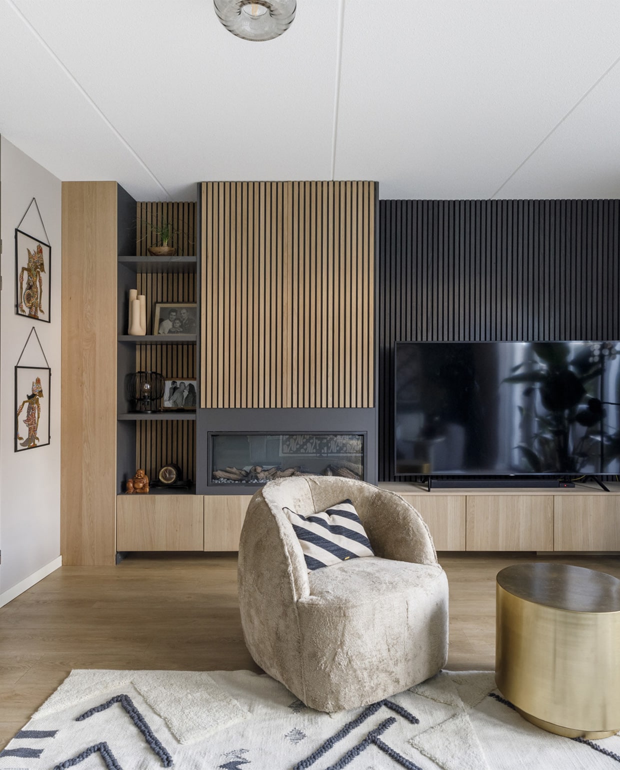 Houten wandpanelen van Noak. Verf muren Urban Taupe FlexaVerf achter de bank Soothing Moss FlexaVerf strook bovenaan Airy Foliage FlexaElektrische blinds in de kleur Moss Grey Jasno ShuttersCanvas doek met een afbeelding van een traditionele batik print Mo-Ca | More Than CanvasZwarte vloerlamp van Good&amp;Mojo EijerkampBank EijerkampFauteuil Vito EijerkampVloerkleden van Malagoon EijerkampPoef Rodeo EijerkampGrijze bijzettafel vtwonenGouden bijzettafel Step van House Doctor vtwonenPlaid van Malagoon vtwonenKussen met panterprint EijerkampRechthoekig kussen EijerkampCrème, beige en blauwe polige kussens van Malagoon vtwonenGestreept kussen (op de fauteuil) van Oyoy vtwonenOp de bijzettafels:Rieten schaal Baskets Beads &amp; BasicsVaas van Bloomingville vtwonenKandelaar van Bloomingville vtwonen. Overig privébezit weer verliefd op je huis aflevering 6 seizoen 17 | styling Marianne Luning | fotografie Margriet Hoekstra