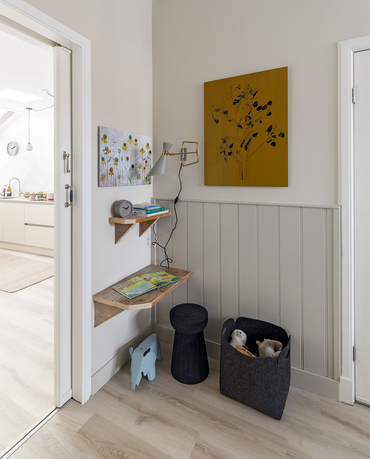 Flexa Creations muurverf Sandy Beach, lak op lambrisering Worthy Clay (flexa.nl). Pvc-vloer met elektrische vloerverwarming, prijs op aanvraag (woninginrichting-aanhuis.nl). Kunstwerk boven bank Abstracte Geometrische Organische Vormen En Lijnen van Diana van Tankeren € 271,-, kunstwerk bij kinderhoek Botanische print judaspenning, okergeel van Joske Kempink € 286,-, kunstwerk bij kinderhoek Helenium, Mandy Disher uit de 1x-collectie € 148,- (werkaandemuur.nl). Bank met bijbehorende kussens € 2899,-, vloerkleed € 417,- (eijerkamp.nl). Vloerlamp € 199,- (itsaboutromi.nl). Letterbakkast € 149,-, plaid van Malagoon € 69,99, wit kussen met strepen van Vestbjerg € 49,95, zwarte krukken van Woood, per stuk € 89,95, opbergmanden van Zeller, per stuk vanaf € 46,95, olifant van Vitra € 95,- (vtwonen.nl). Wandlampen, per stuk € 119,- (zuiver.com). Foto van Vlieland, prijs op aanvraag (vliehors-expres.nl). Wandbureaus en -planken gemaakt van oud tv-meubel, prijs op aanvraag (md-sign.nl). Overig privébezit. Voor informatie eethoek zie foto 1. JA | vtwonen weer verliefd op je huis  seizoen 17, aflevering 11 | styling Fietje Bruijn | fotografie Margriet Hoekstra