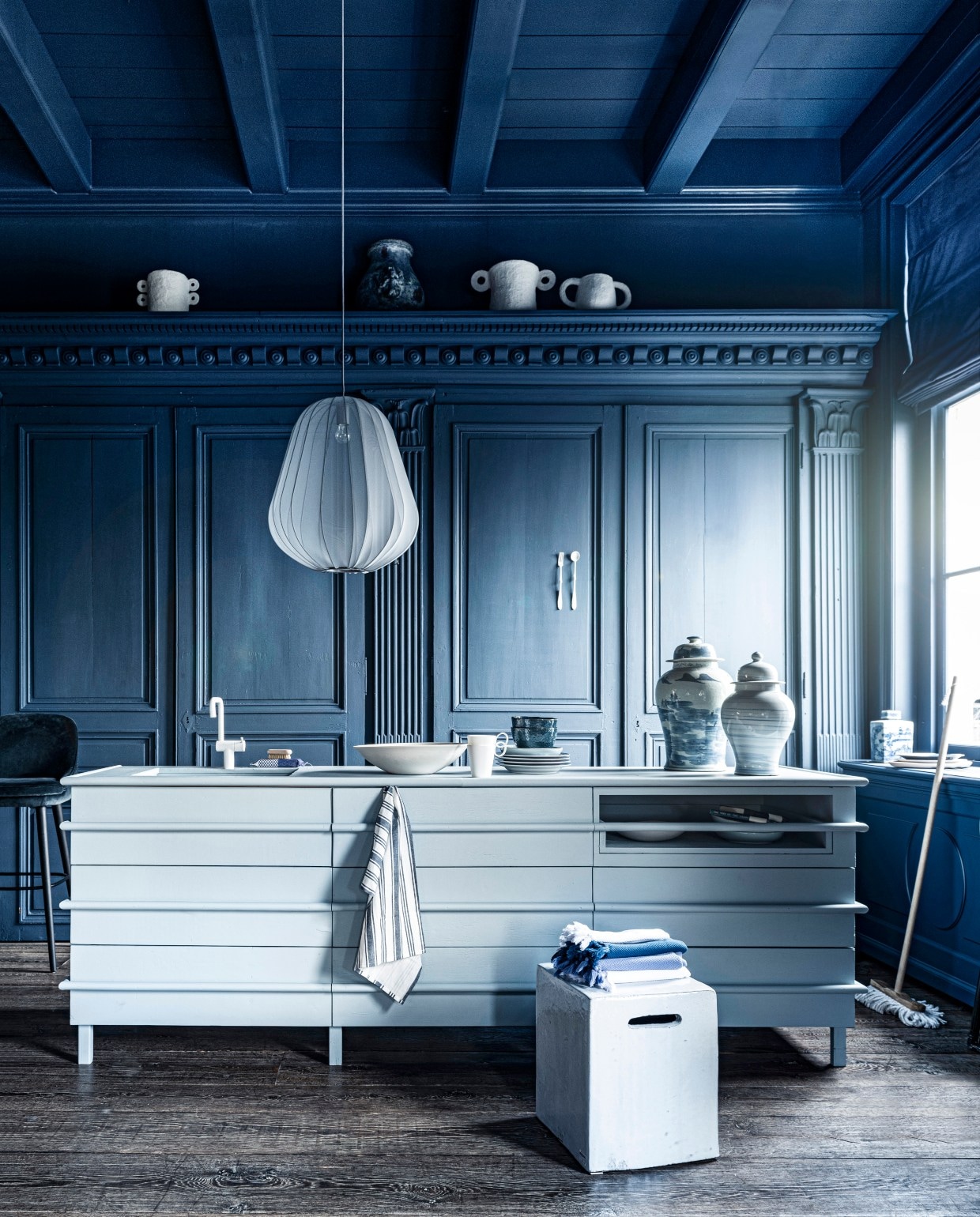 Blauw-witte potten, per stuk € 149,95, vierkante pot € 44,95, bezem € 13,95(loods5.nl). Witte pot van Serax bovenin links € 54,-, witte pot bovenin midden € 54,-,kraan prijs op aanvraag, witte schaal, prijs op aanvraag, vierkante kruk € 2241,-(badenbaden.nl). Donkere grote vaas boven op plank, set van 4 € 1936,-, 18e-eeuwsehouten vloer, per m² € 168,19 (pietjonker.nl). Gordijnstof 295 breed, per meter€ 103,- (wva.nl). Keukeneiland prijs op aanvraag (com-anders.nl). Vork en lepel€ 40,- (lisannevanzanten.nl). Hamamdoeken vanaf € 9,60 (ottomania.nl). Gestreeptetheedoeken, set van 3 € 9,99 (hm.com). Barkruk € 2174,- (covanderhorst.nl). Zeep€ 22,50, zeepborstel € 11,50, notitieboeken per stuk € 19,95 (maisonnl.com). Wittemok € 8,95, blauw-wit bord € 13,95 (hkliving.nl). Houten dienblad Zanat € 113,-(homestede.nl). In het midden bord van Leonardo, Ø 23 cm € 9,95, blauwe kom vanLeonardo, Ø 15 cm € 9,95, Balloon hanglamp van Bolia € 469,- (vtwonen.nl).Overig privébezit. JA | vtwonen 07-2020 | styling Liza Wassenaar | fotografie Sjoerd Eickmans