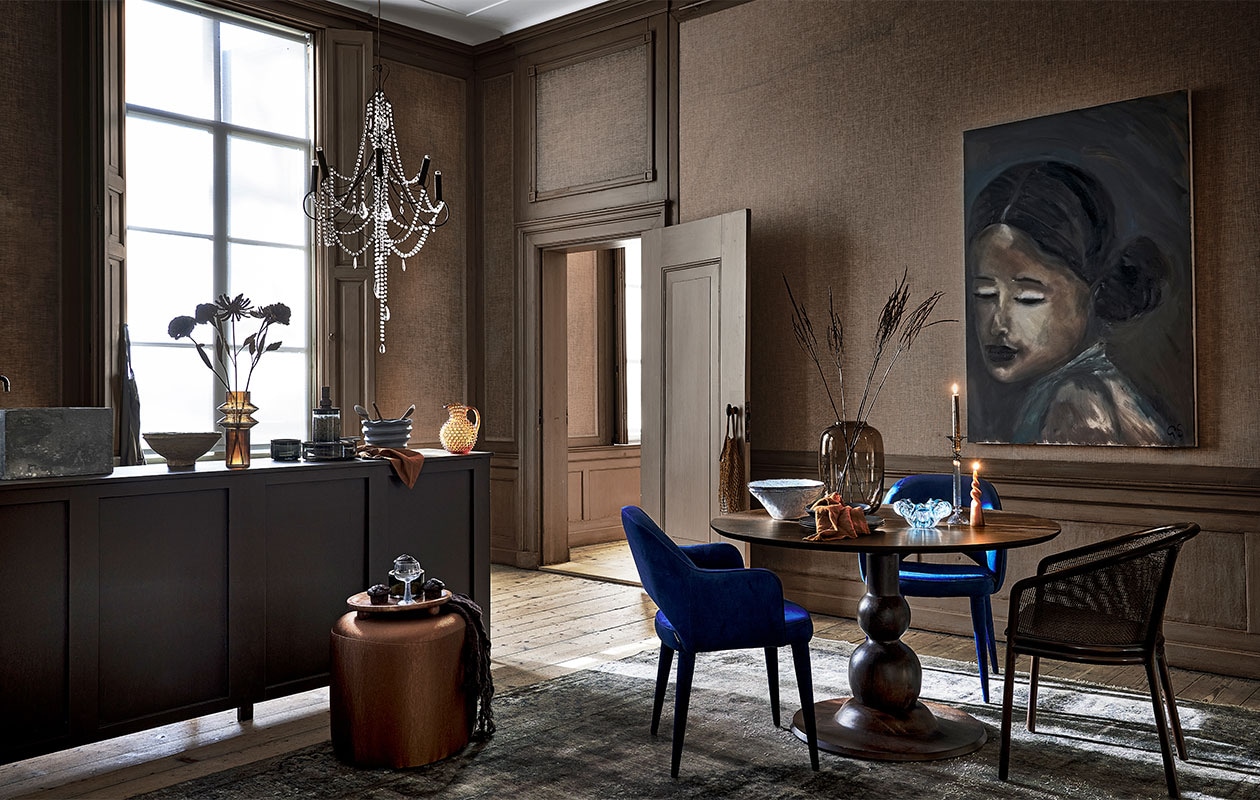 Keuken gemaakt door Combitex, prijs op aanvraag (com-anders.nl). Linnen schort € 29,99, keramieken lepels, per stuk € 9,99, dienblad op pootjes € 34,99 (sissy-boy.com). Bruin linnen servet € 4,50, bruine glazen karaf € 100,- (paviljoennoord.com). Papier-maché schaal € 39,95, bruine glazen vaas € 49,95, voorraadpotten met houten deksel, per stuk vanaf € 21,95, wijnglas op blauwe poot € 10,40, blauwe schaal met streeptextuur € 33,60, lichtblauwe schalen, per stuk € 34,90, donkerblauwe borden, per stuk € 16,95, donkerblauwe kommen, per stuk € 19,95, blauwe glazen schaal € 39,-, blauwe glazen kandelaar € 29,95, eetkamerstoel met webbing rugleuning € 649,- (nordal.eu). Metalen bloemen, per stuk € 19,95 (hamptonsbergen.nl). Kroonluchter € 1450,- (brechtjeolsthoorn.nl). Bruine gestoffeerde poef vanaf € 332,75 (rapture.amsterdam). Vloerkleed prijs op aanvraag (ebru.nl). Blauwe fluwelen stoelen, per stuk € 425,- (polspotten.nl). Ronde eettafel van BePureHome, 120 cm (Ø) € 629,- (basiclabel.nl). Bruine glazen vaas € 110,- (homestede.nl). Gedraaide kaars € 4,95 (dille-kamille.nl). Olieverfschilderij prijs op aanvraag (gracespiegel.com). Overig privébezit. vtwonen 1-2022 | styling danielle verheul | fotografie sjoerd eickmans | locatie Landhuis Oud Amelisweerd (landhuisoudamelisweerd.nl) | assistentie sanne ketelaar, meike linthorst, willem tjalma