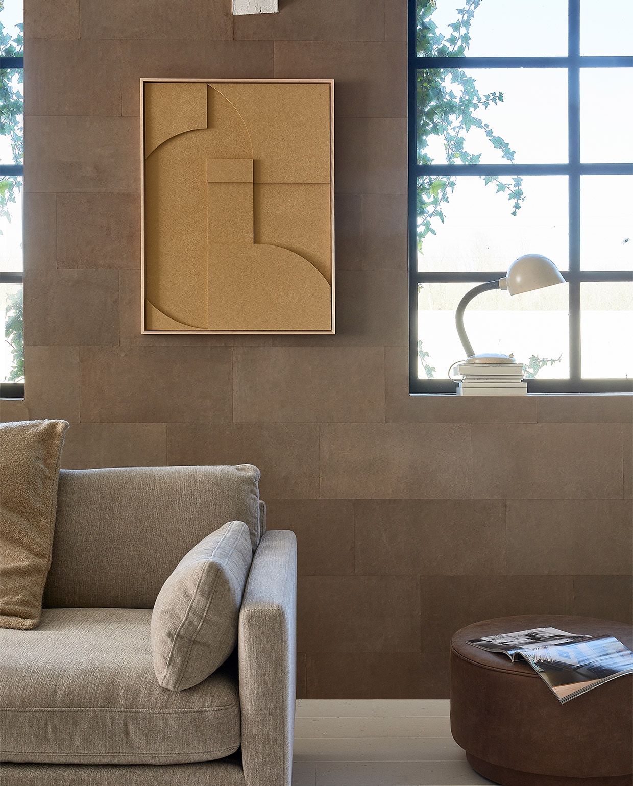 Leren wandtegels in kleur Desert, per m2 € 69,95 (enzopellini.com). Bank Summer in kleur Latte, 4,5 zits, 335 cm (b) € 2530,-, aluminium salontafel Floss, 60 cm (Ø) € 275,- (zuiver.com). Fauteuil Juno vanaf € 1549,- (eyye.nl). Handgemaakt wollen vloerkleed Hjorstvang, 160×230 cm € 349,- (ikea.nl). Leren loungemat, 150x100x6,5 cm (lxbxh) € 379,- (nahka.nl). Ecoleren poef van vtwonen in kleur Cognac, 60×36 cm (Øxh) € 159,-, plaid op bank Sahara van Malagoon, 150×125 cm € 59,95, papieren hanglamp Leena, 50×52 cm (Øxh) € 144,95, kussen, 50×70 cm € 41,90, vaasjes op vensterbank vanaf € 33,50 (vtwonen.nl). Keramische voet schemerlamp € 195,- (neeflouis.nl). Kruk € 30,- (vandijkenko.nl). Aan de wand reliëfkunstpaneel in kleur Sand, 63×83 cm € 469,-, zijden lampenkap, 36×58 cm (Øxh) € 159,- (hkliving.nl). Overig privébezit. JA | vtwonen 05-2022 | styling Fietje Bruijn | fotografie Dennis Brandsma\n