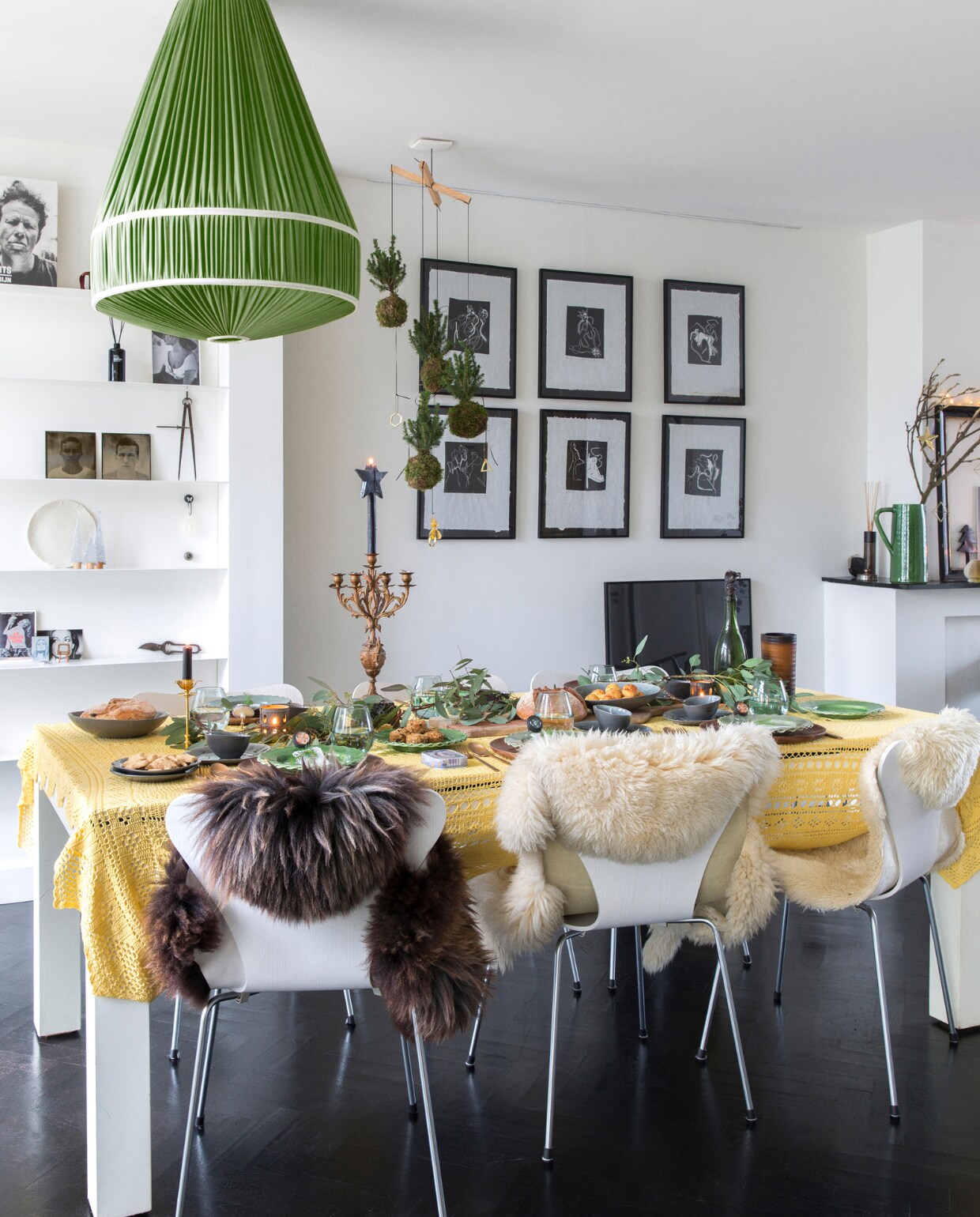 Eettafel maatwerk Woodies at Berlin, tafelkleed rommelmarkt, vlinderstoelen Fritz Hansen, vachten Ikea en markt. Servies, glaswerk, bestek, kaars met ster, groene keramieken kan K’ook!, grote kandelaar familiestuk, kleine kandelaar Goed in Stijl, groene takken Floribundus. Mobile met kokedama’s BoulevardB, hanglamp IJ-Hallen. Zwarte lijsten ’t Kwassie, kunst Frenk van Heeswijk. Op de wandplanken van boven naar beneden en v.l.n.r. boek Waits van Anton Corbijn, foto Brigitte Bardot Goed in Stijl, geurstokjes Frau Tonis Parfum (ook op de schoorsteenmantel), portretfoto’s zoons gemaakt door Sevilay Maria, passer Huibs opa. Visgraatvloer Van Dijk &amp; Ko, zwart geschilderd en gelakt Sigma, muurverf RAL 9010. Overig onbekend. vtwonen 13-2022 | styling Barbara Natzijl | fotografie Margriet Hoekstra | tekst Sunna Borghuis