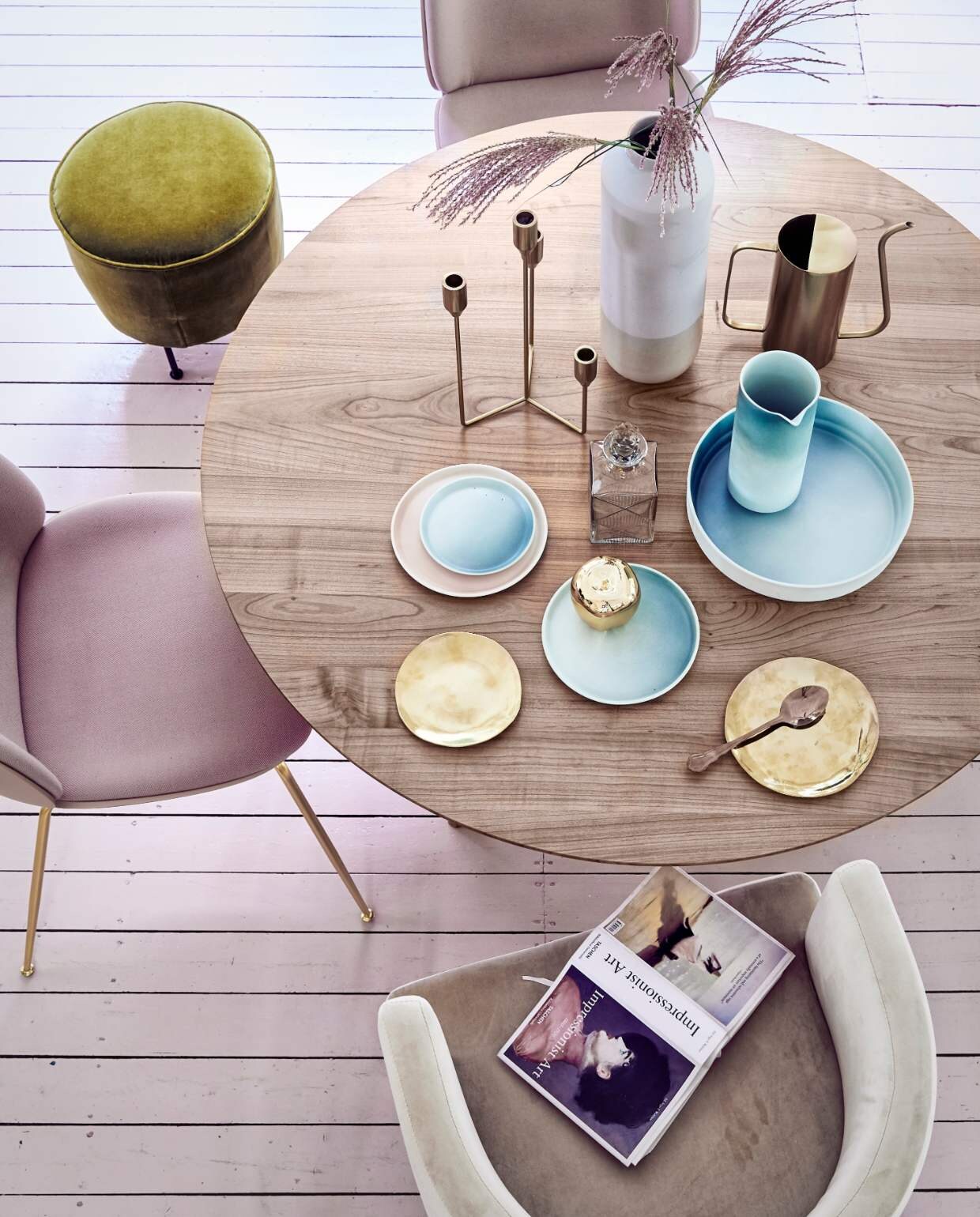 Romantische woonstijl: ronde eettafel met pastel servies en roze velvet stoelen