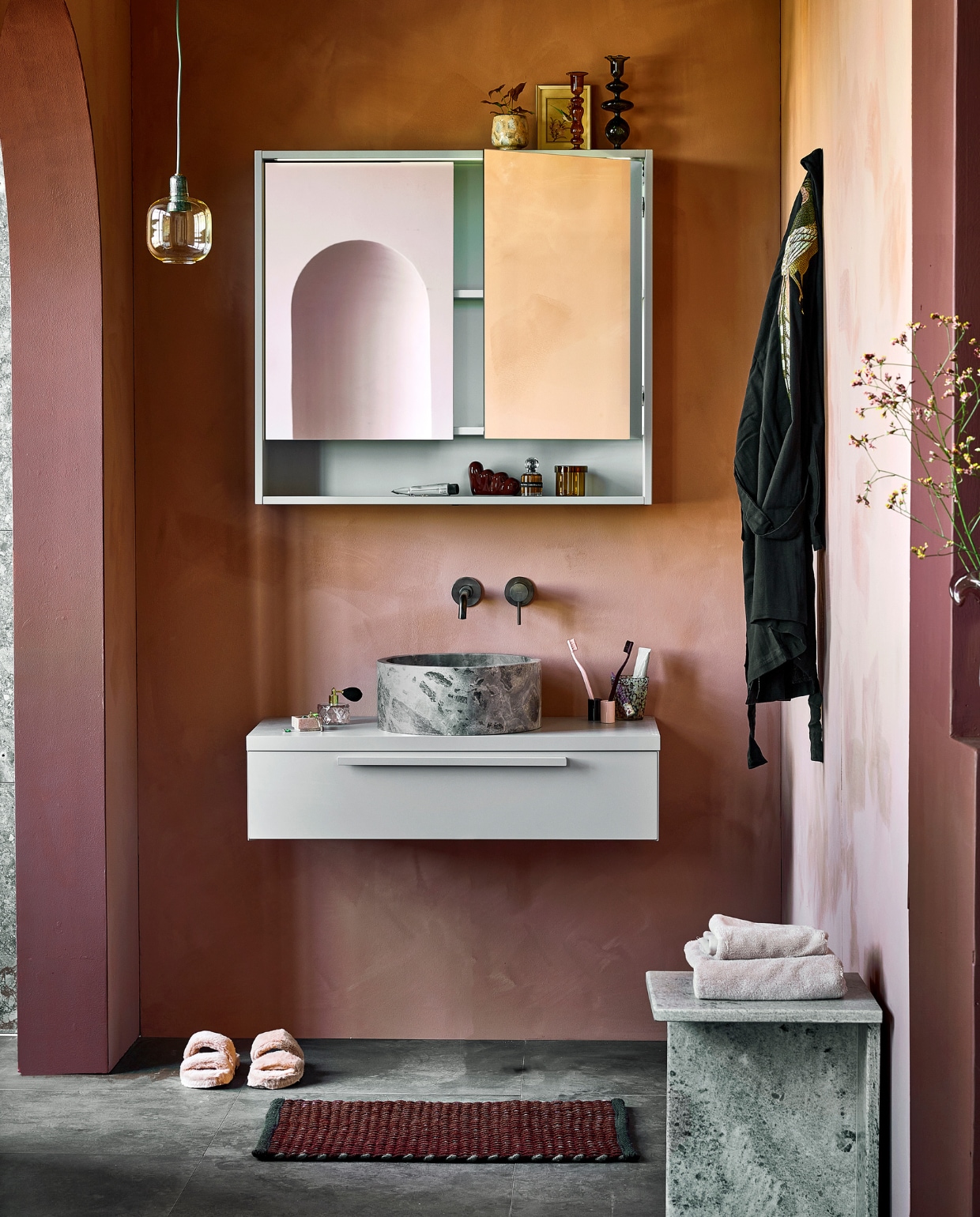 Spiegelkast Handy Beauty vanaf € 590,- (pag. 88). Waskom in marmer Circle Silver Fantasy € 630,- (pag. 88). Onderkast Tidy, grijs vanaf € 515,-(pag. 88). Tegels Raw Antracite, 60×60 cm per m2 € 59,- (pag. 92). M.m.v. vestingh.nl (muurkleur Terra Pink No.102, kleur van kolom en rand toog Merlot Mania No. 123), zarahome.com (sloffen, handdoeken), vtwonen.nl (hanglamp Amp van Normann Copenhagen), hay.nl (bruin glazen opbergpotje Container S, tandenborstels Tann, tandenborstelhouder), nordal.eu (marmeren bijzettafel Glina, glazen kandelaars, roze vaas, gespikkeld drinkglas, roze marmeren bakje), stories.com (parfum, tubes, sieraden), hammam34.com (zwarte Kimono The Pheasant). Overig privébezit. vtwonen catalogus 10 | styling Kim van Rossenberg | Fotografie Sjoerd Eickmans