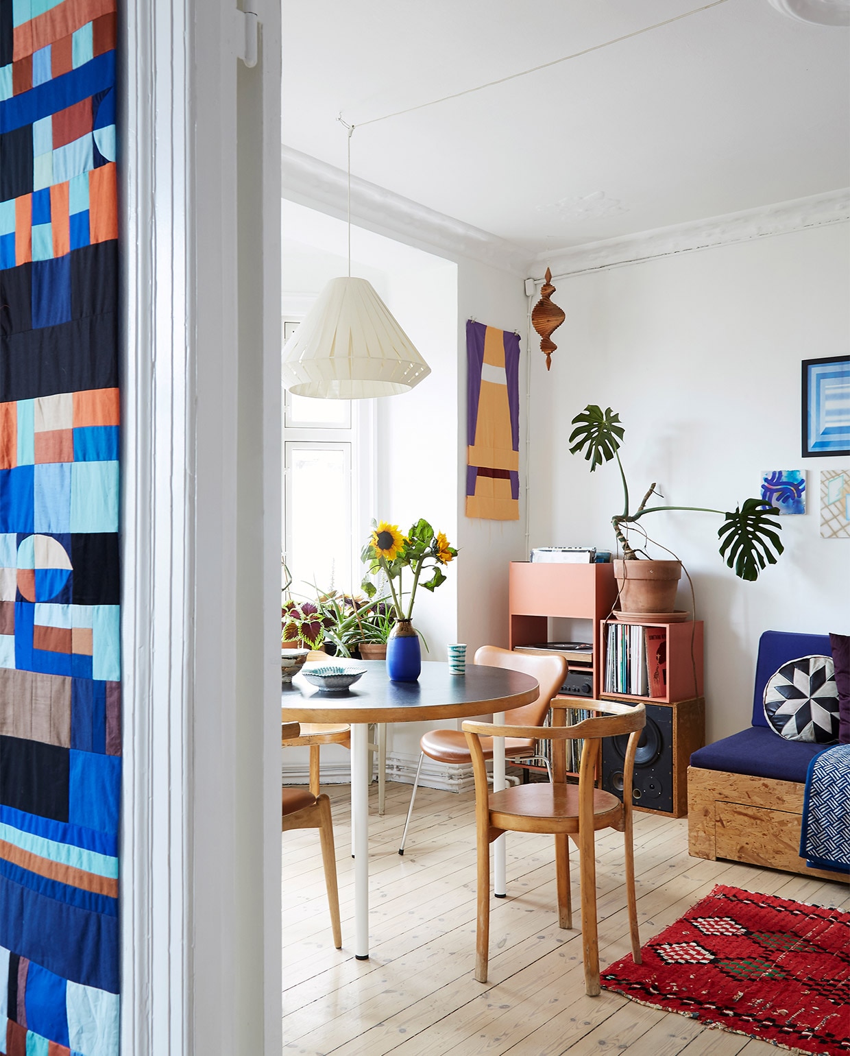 Tafel en designstoelen tweedehands. Hanglamp erfstuk. Gestapelde kastblokken en wandkleden zelfgemaakt. Vloerkleed uit Marokko. Kussen uit Istanboel. vtwonen binnenkijken special 2022 | styling Rikke Graff Juel | fotografie Annita Behrendt
