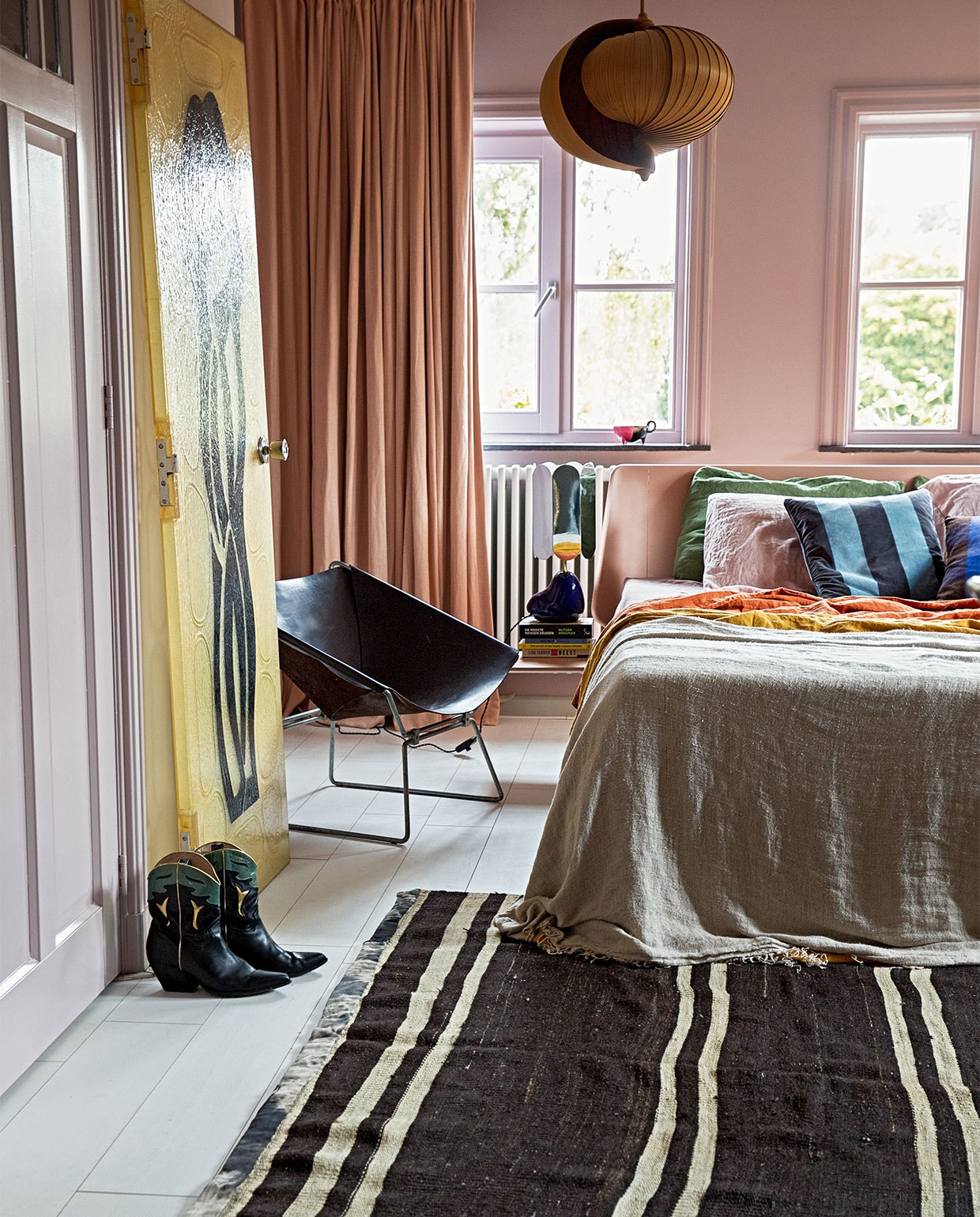Verf wand Peach Blossom van Little Greene. Gordijnen Soft Salmon Amor Linnen van Vadain. Fauteuil Midcentury design van Pierre Paulin Polak, plafondlamp vintage Moon van Hans Agne Jakobsson, kunststuk tegen wand Fiberglass Deur Midcentrury via Best Wel Hip. Lamp nachtkastje voet van Ferm Living en kap van Hay. Bed Auping. Sprei HKliving. Kussens bedlinnen van Casa Comodo. Kleed Turks vintage. Laarzen Elena Iachi. Overig onbekend. vtwonen 05-2022 | styling Ilona Jongepier | fotografie fotografie Dana van Leeuwen