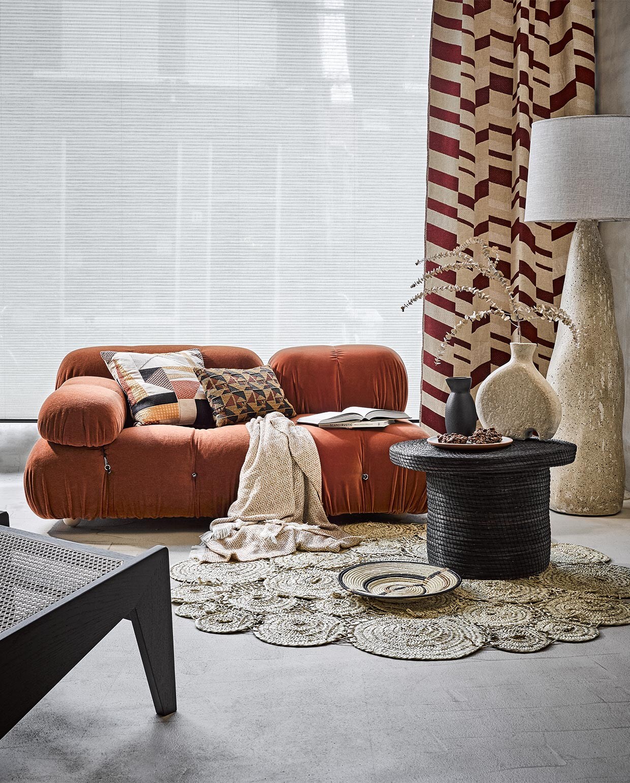 Gordijnen gemaakt door Meta Poulain van verschillende kleuren standaard gordijnen Dytâg, 145×300 cm € 59,95 en lichtgroen gordijn Silverlönn, 145×300 cm, per paar € 19,99, plaid op bank, prijs op aanvraag (ikea.nl). Bamboe rolgordijnen, 90×180 cm € 19,99 (xenos.nl). Ronde rieten wandlamp € 1199,-, stuc op wand en vloer, prijs op aanvraag, lamp links € 599,95 (lanena-home.com). Kussens op bank van gordijnstof Uni Boost 16 natural van Vadain, per meter vanaf € 35,- (maximavloeren.nl). Slippers € 31,- (japansewinkeltje.nl). Kussens van links naar rechts op bank: terra stone washed, 50×70 cm € 146,-, geel stone washed, 50×70 cm € 167,-, groen vice versa jaquard stone washed kelim bronze € 131,-, groen vierkant met zwarte streep kelim Turkije, 50×50 cm € 49,-, langwerpig met print Out of Africa € 212,50, groen achter plant in hoek € 175,-, geel kelim Turkije, 50×50 cm € 49,-, langwerpig terracotta met zwarte rand, 50×70 cm € 167,-, met rode streep van Libeco, 63×63 cm € 184,-, grote zwarte vaas Adko € 230,-, kleine gevlochten schaal, 20 cm (Ø) € 29,-, waaier € 37,-, groene karaf art deco amber € 63,- (couleurlocale.eu). Droogbloemen (plantje.nl). Kussen op grond geel met wit van stof Li 876 22 van Elitis, per meter € 225,-, klein kussen met print links op bank van stof Lr 33122 van Elitis, per meter € 245,-, kussen linksachter op bank met ronde stippen print Co 196 37 03 zonder vulling € 79,-, kleed op grond met cirkels Ta 1127406 van Elitis € 470,- (loggerewilpower.com). Zwarte salontafel € 395,-, zwart met beige bakje € 9,- (householdhardware.nl). Houten college theekop van Serax, 0,15 liter € 13,50, beige bord Terres de Reves in Misty Grey van Serax, 22 cm (Ø) € 18,40 (vtwonen.nl). Houten dienblad op bank € 254,- (homestede.nl). Witte siervorm op tafel, prijs op aanvraag, boek Japan op tafel € 29,99 (hm.com). JA | vtwonen 03-2022 | styling Liza Wassenaar | fotografie Alexander van Berge