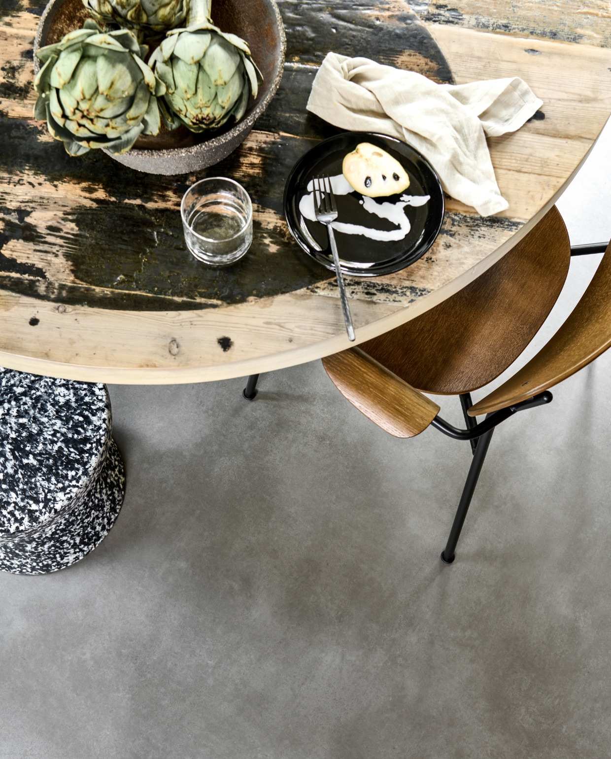 Novilon vloer Gruis, per m² € 35,65.M.m.v. vtwonen.nl (houten eetkamerstoel van Menu, gemêleerde kruk van Normann Copenhagen, bord van Serax), interiorcowboys.com (eettafel, aardewerken etagère), zarahome.com (glas, linnen servet, vork). vtwonen 13-2022 | productie Tanja Saarberg | styling Sanne Ketelaar | fotografie Sjoerd Eickmans