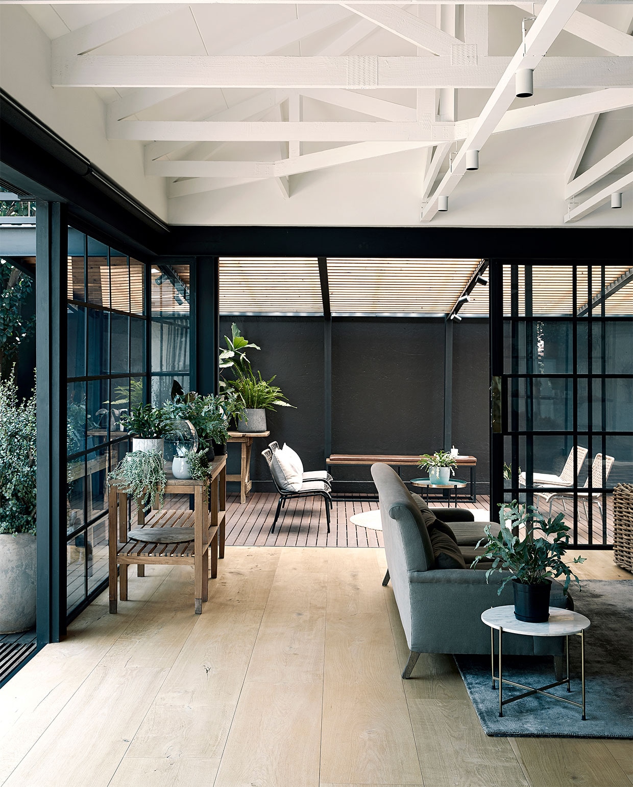 Bank Mezzanine Interiors. Rieten bank Weylandts. Bank rechts en stalen stellingkast Live Simple. Tapijt en ronde bijzettafel Hertex. Plantentafel en bloempotten kringloopwinkel. Overig onbekend. vtwonen binnenkijken special 2021 | productie Bureaux | styling Sven Alberding | fotografie Elsa Young