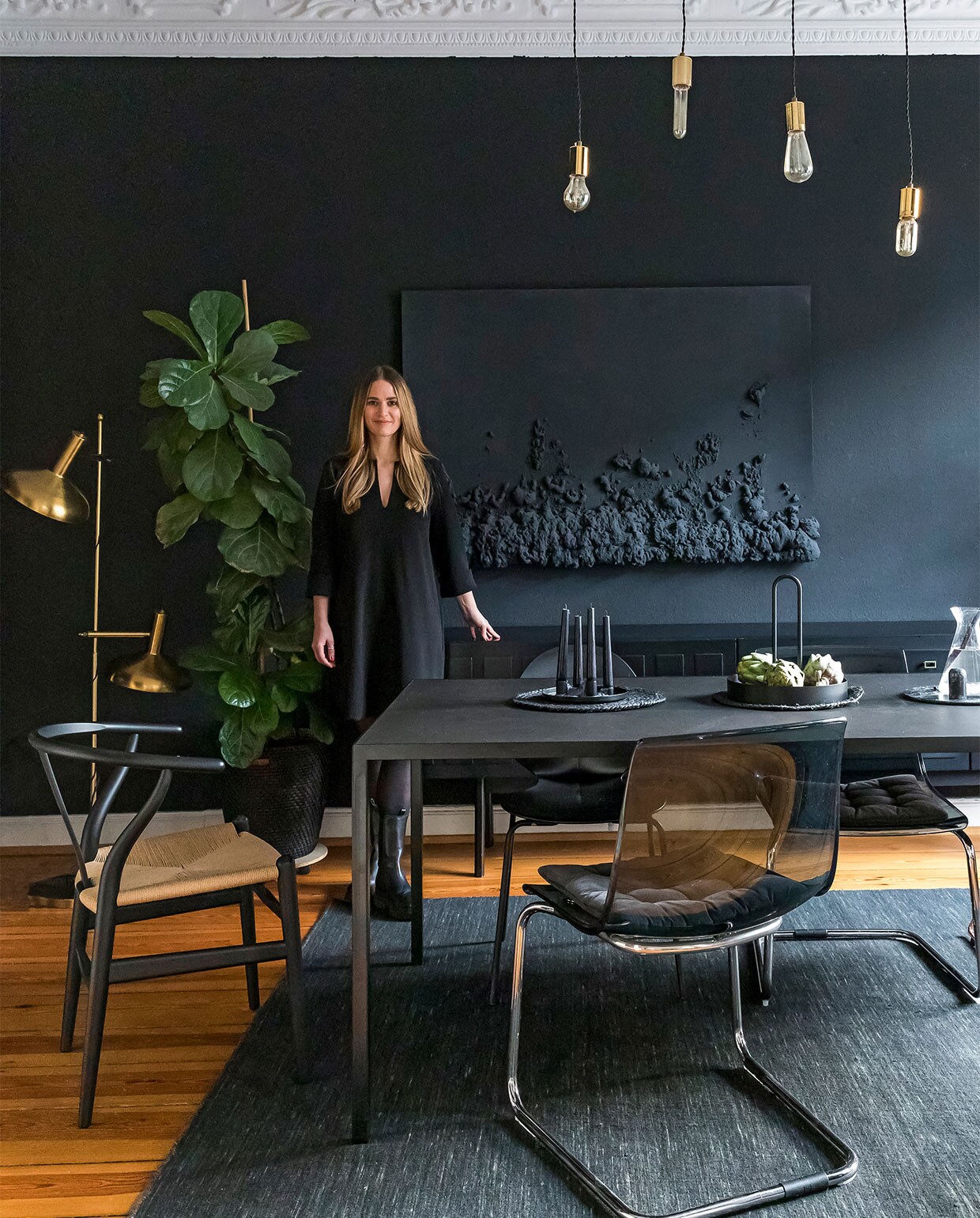 Muurverf Kleines Schwarz Schöner Wohne Farbe. Gouden vloerlamp tweedehands. Wandkunstwerk door Sabrina gemaakt. Zwartgeverfd dressoir erfstuk. Eettafel op maat gemaakt. Stoel links CH24 Wishbone Carl Hansen, overig tweedehands verzameld. Vloerkleed Rugvista. Overig onbekend. vtwonen special 121-2022 | productie &amp; fotografie Anne-Catherine Scoffoni