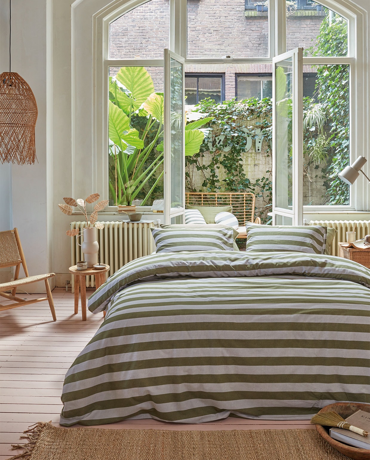Katoenen dekbedovertrek van vtwonen collectie Bold Stripe, kleur Green,140×200/220 cm € 59,95, 200×200/220 cm € 109,95, 240×200/220 cm € 119,95, 260×200/220 cm € 139,95 (ook verkrijgbaar in Peach). Op de buitenbank gestreept kussen Bold Round, gerecycled acryl en polyester, kleur Green, 40 cm (Ø) € 49,95, gestreept kussen Bold Square, gerecycled acryl en polyester, kleur Green, 45×45 cm € 44,95. M.m.v. sissy-boy.eu (fauteuil, rotan takken), nordal.eu (hanglamp, nachtkastje), loods5.nl/goods (houten bijzettafel), letoile.store (mok, wierookhouder, vloerkleed), mimiettoi.com (houten schaal, tafellamp). Overig privébezit. vtwonen 05-2022 | productie Tanja Saarberg | styling Danielle Verheul | fotografie Richard Smit