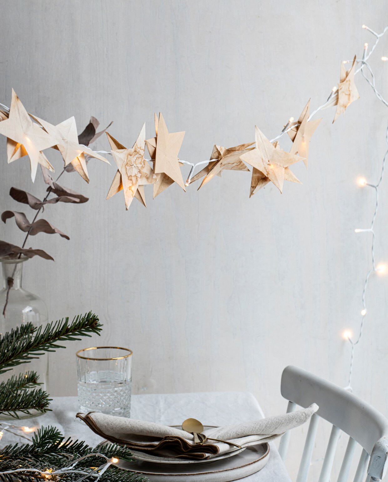 Houten eetkamerstoel, soortgelijke Lotta € 99,-. Gewassen wit linnen tafelkleed € 49,99, glas met reliëf en goudkleurige rand, soortgelijk vanaf € 5,99, porseleinen bord, bruin gespikkeld € 5,99, wit keramieken bord € 9,99, 3-delige bestekset € 9,99, katoenen servet, set van 2 € 7,99. Overig privébezit. vtwonen special Kerst Couture 12-2022 | styling Janneke Peters | fotografie Louis Lemaire