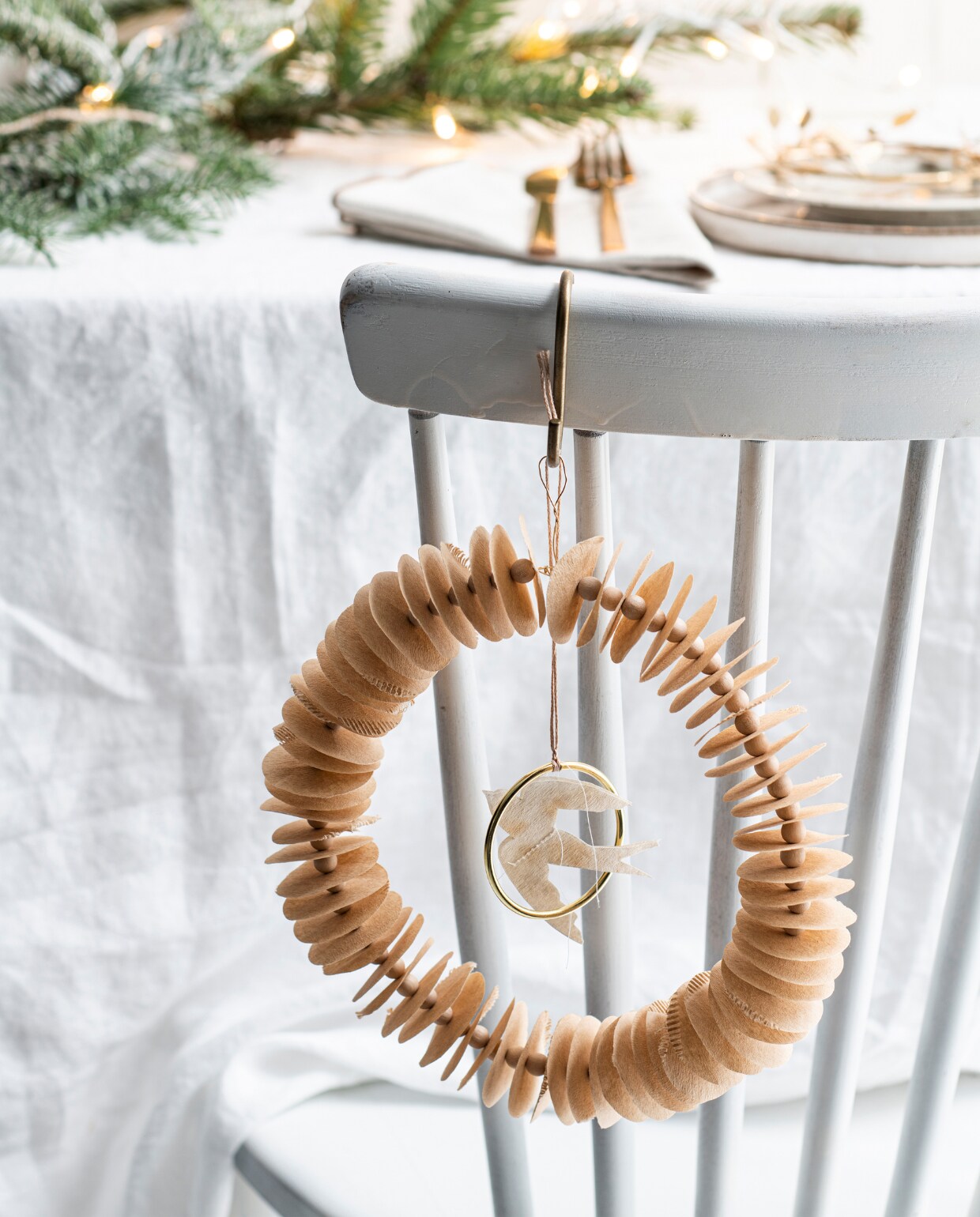 Houten eetkamerstoel, soortgelijke Lotta € 99,-(gewoonstijl.nl). Gewassen wit linnen tafelkleed € 49,99, glas met reliëf en goudkleurige rand, soortgelijk vanaf € 5,99, porseleinen bord met bruine spikkels € 5,99, wit keramieken bord € 9,99, 3-delige bestekset € 9,99, katoenen servet, set van 2 € 7,99. Goudkleurige metalen S-haak van Nordal € 3,15. Overig privébezit. vtwonen special Kerst Couture 12-2022 | styling: Janneke Peters | fotografie Louis Lemaire
