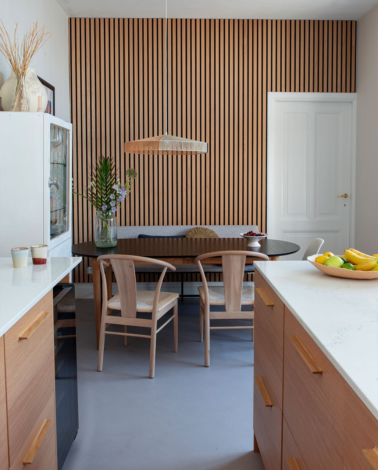 Keuken Kvik met composietblad in marmerlook, akoestische eikenhouten wandpanelen en houten stoelen Lijn M, eettafel Jysk, hanglamp HKliving, vintage apothekerskast uit Polen, bankje Wehkamp. vtwonen DIY special 04 | styling Jeske Weel | fotografie Caroline Coehorst