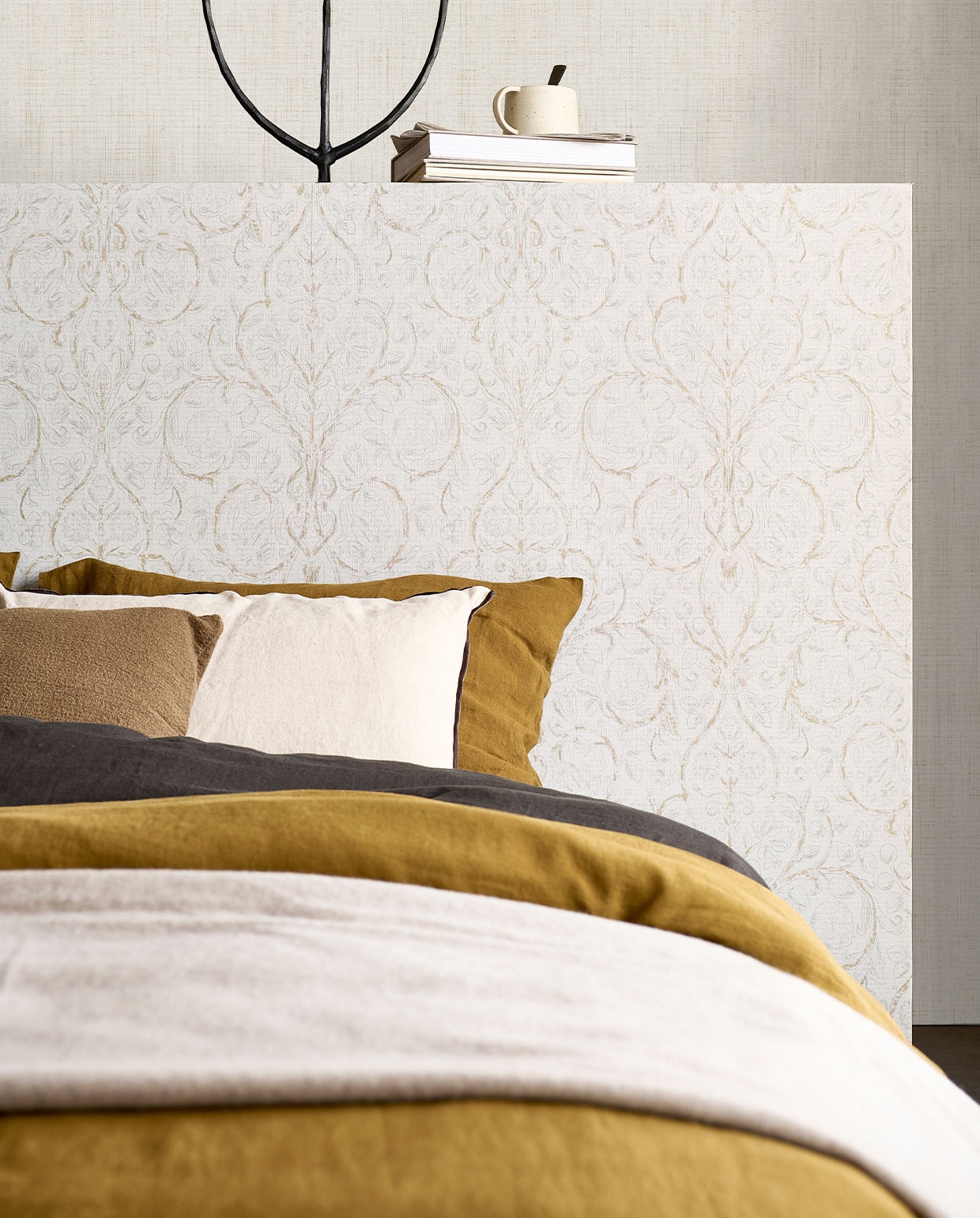 Behang op hoofdbord Classic Curl Light Grey, op achterste wand Linnen Gold, 53 cm breed, rol van 10 meter €29,99 (classic Curl ook verkrijgbaar in Sea Green).M.m.v. pure-original.nl (muurverf Fresco in kleur Old Flax), paviljoennoord.com (linnen dekbedovertrekken, linnen kussenslopen, olijfgroen kussen), letoile.store (mok), sissy-boy.com (metalen kandelaar, plaid), zarahome.com (wit kussen). Overig privébezit. vtwonen 06-2022 | productie Tanja Saarberg | styling Danielle Verheul | fotografie Sjoerd Eickmans | assistentie Kula van den Broek