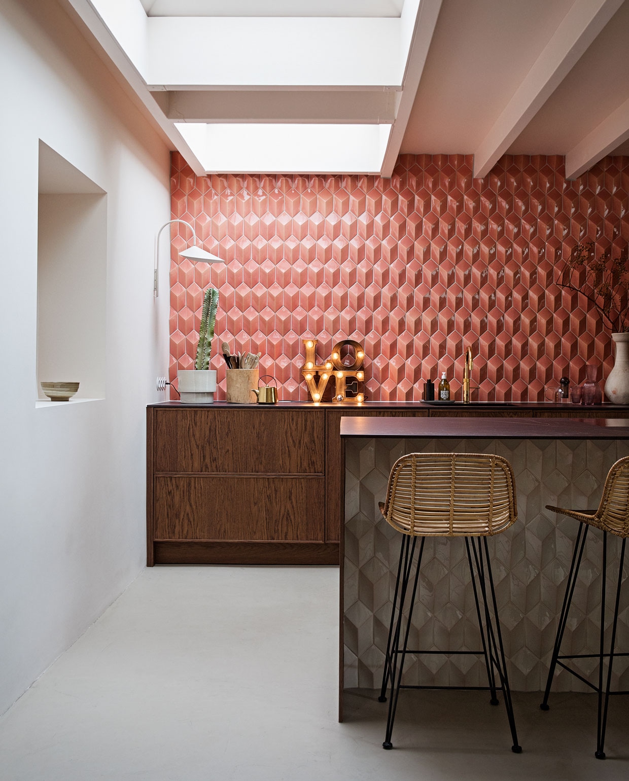 Barkrukken, theepot en kom in nis HKliving. Wandlamp Ferm Living. Love lamp Sissy-Boy Homeland. Tegels Constellation kleur Flamingo Baby via Quintalisque. Kraan Quooker. Houten pot Household Hardware. Bloempot H&amp;M Home. Planten Blóm. Overig herkomst onbekend. vtwonen 2-2022 | styling Ilona Jongepier | fotografie Dana van Leeuwen