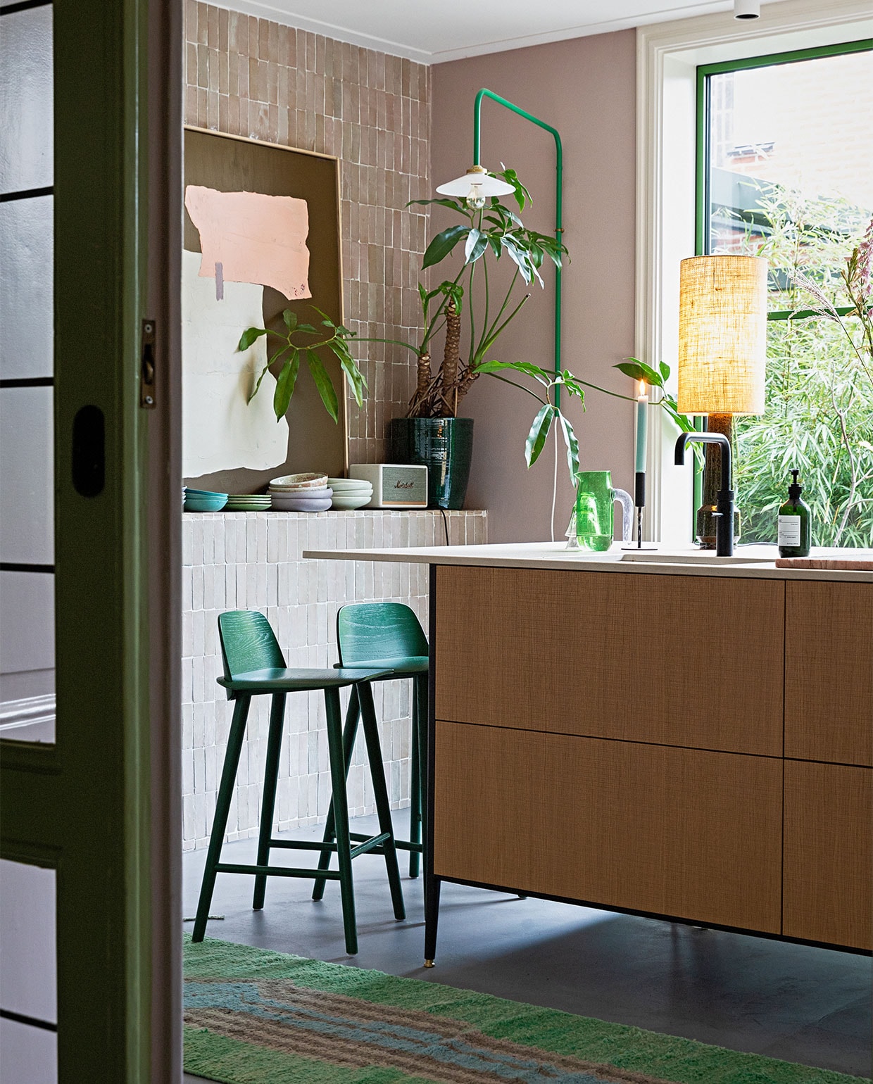 Groene lamp aan muur Valerie Objects. Tegels Bejmat Gris rose Marokkaanse tegels via Design Tegels. Schemerlamp en kunst HKliving. Kandelaar Hema. Kan Hay. Plantenpot Serax. Muziekbox Marshall. Servies mix van onder andere Home Chef en 70’s ceramics van HKliving. Krukken Nerd van Muuto. Keuken Unit van Cesar Kitchens. Kleed vintage berber. Aluminium pui in kleur Varen Groen. Lamp plafond onbekend. vtwonen 05-2022 | styling Ilona Jongepier  | fotografie Dana van Leeuwen
