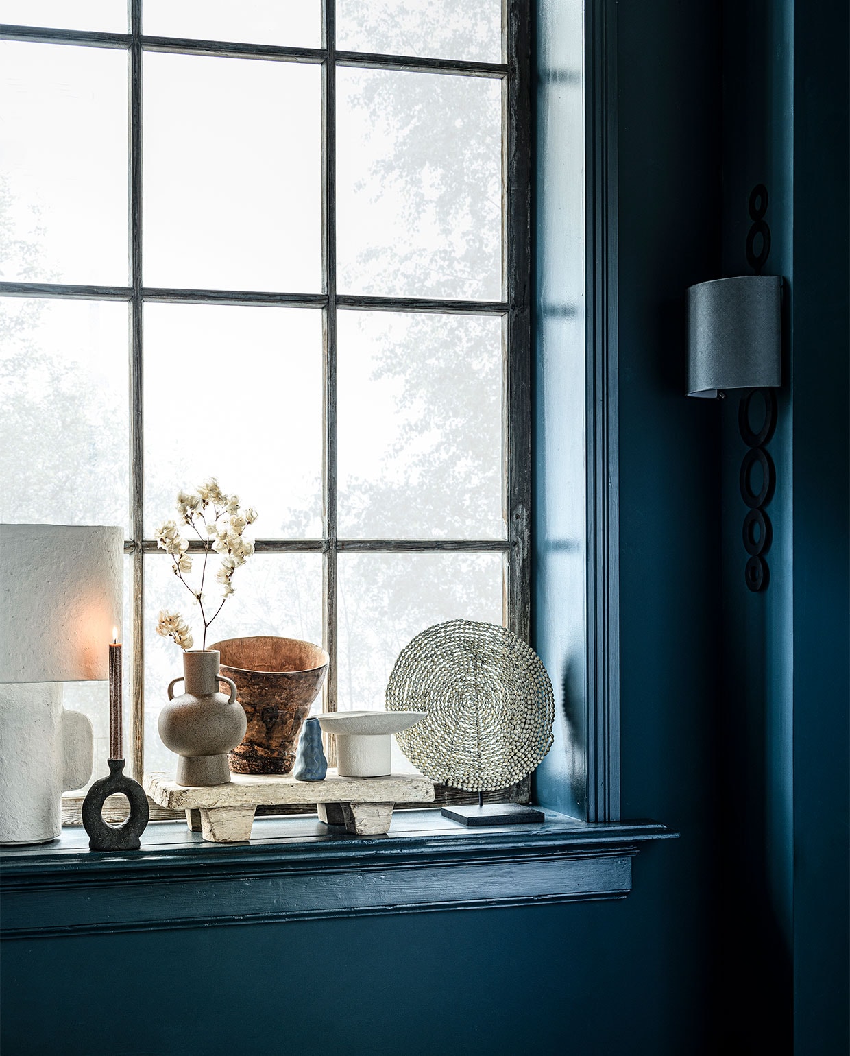 Op de wand krijtverf Steel Blue, per liter € 39,25 (pure-original.nl). Tafellamp € 219,- (loods5.nl/design). Zwarte keramieken kandelaar, 9,5x4x17 cm (lxbxh) € 97,-, houten dienblad op pootjes € 80,-, witte keramieken schaal op poot € 190,- (studio-yen.com). Beige vaas met oren € 12,99 (hm.com). Houten vaas € 22,90 (loods5.nl). Blauwe minivaas € 14,95 (klevering.nl). Object van schelpen op voet € 149,- (badenbaden.nl). Wandlamp Selva van Vaughan € 905,-(wva.nl). vtwonen 11-2020 | styling Danielle Verheul | fotografie Sjoerd Eickmans